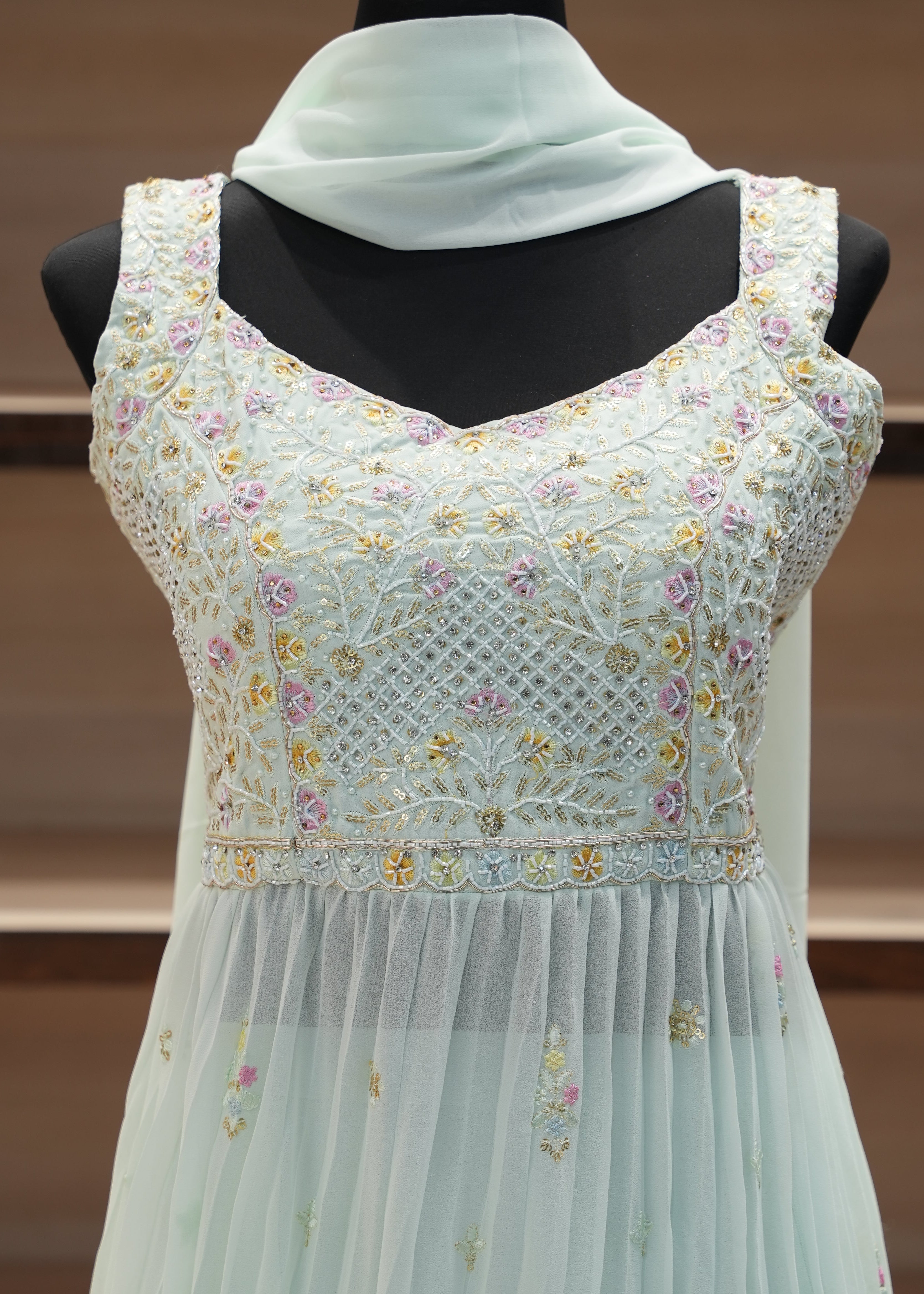 White dress with floral embroidery on a mannequin against a brown background