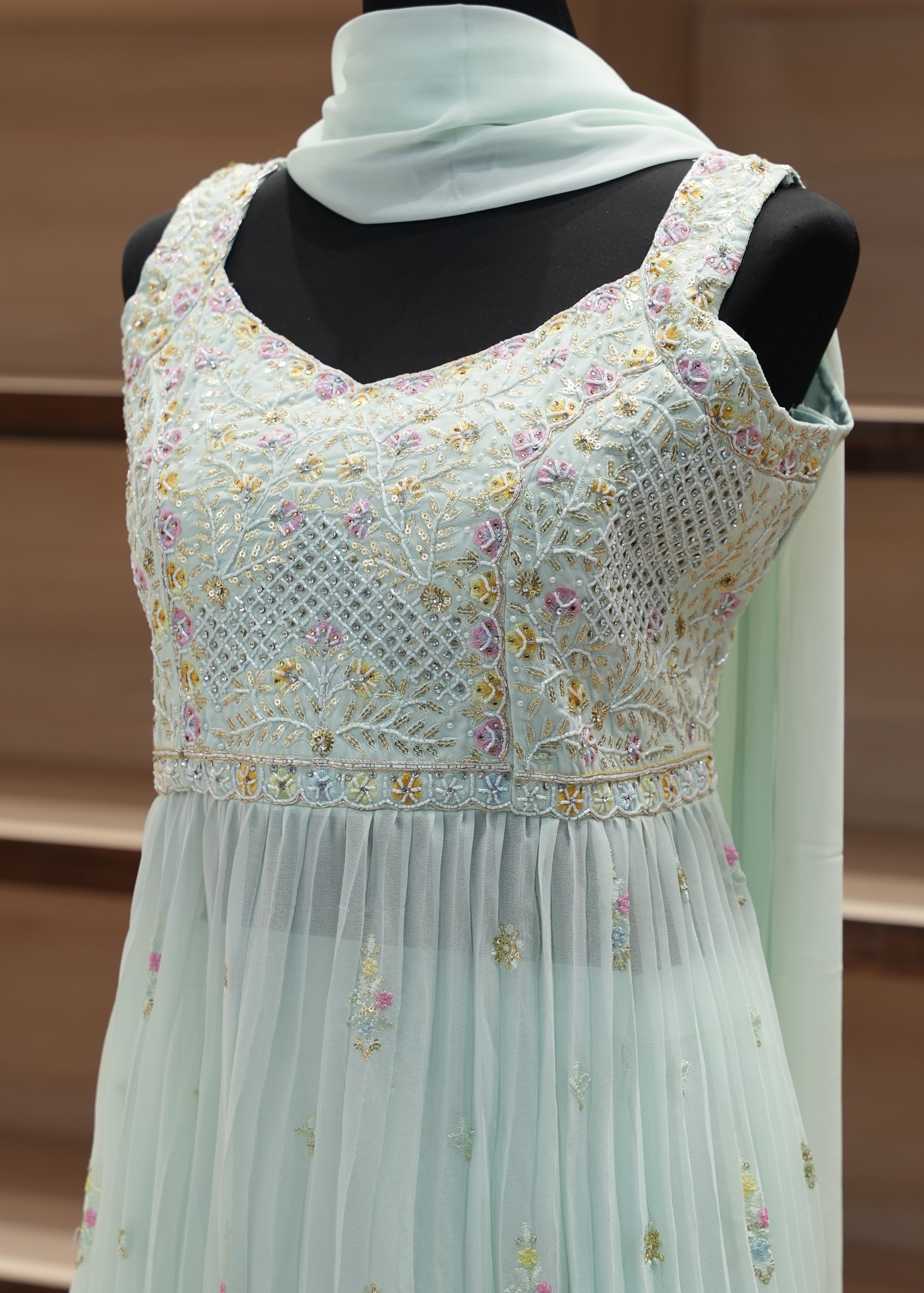 Light blue dress with floral embroidery on a mannequin against a brown curtain background