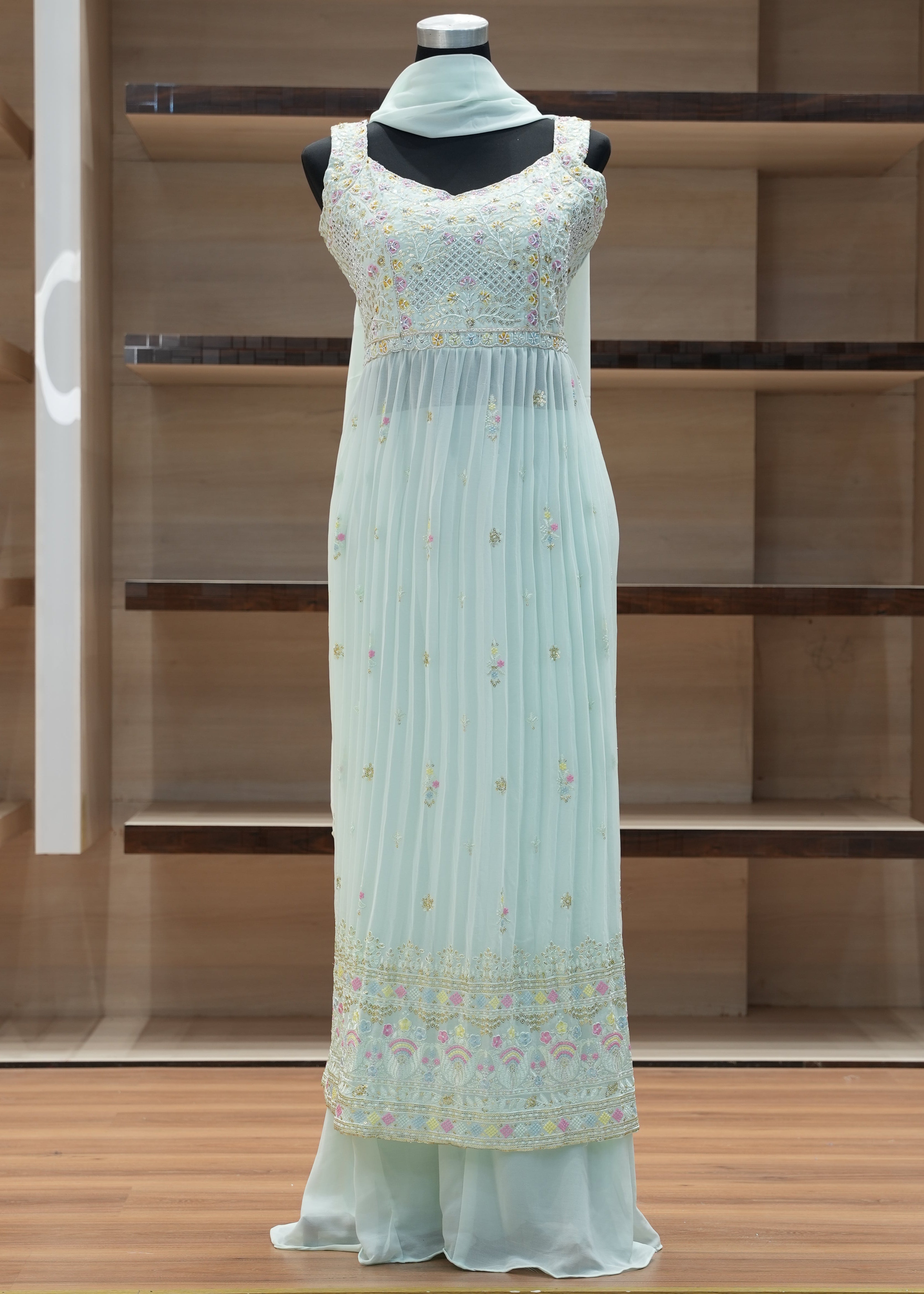 Light blue dress with floral patterns on a mannequin against a wooden background