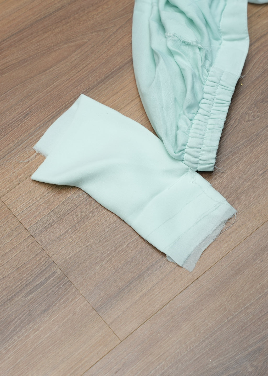 Light green baby pants on a wooden floor