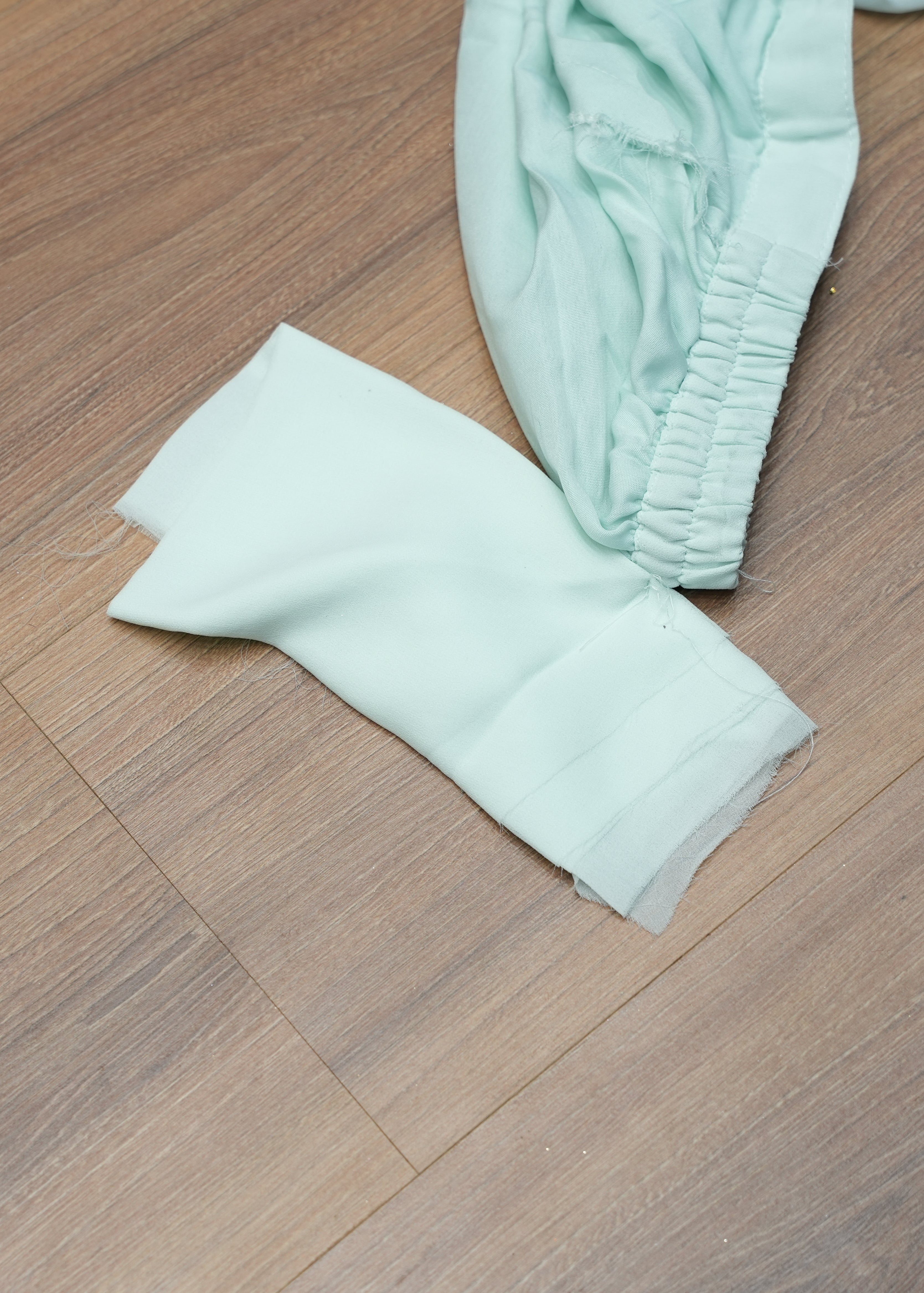 Light green baby pants on a wooden floor
