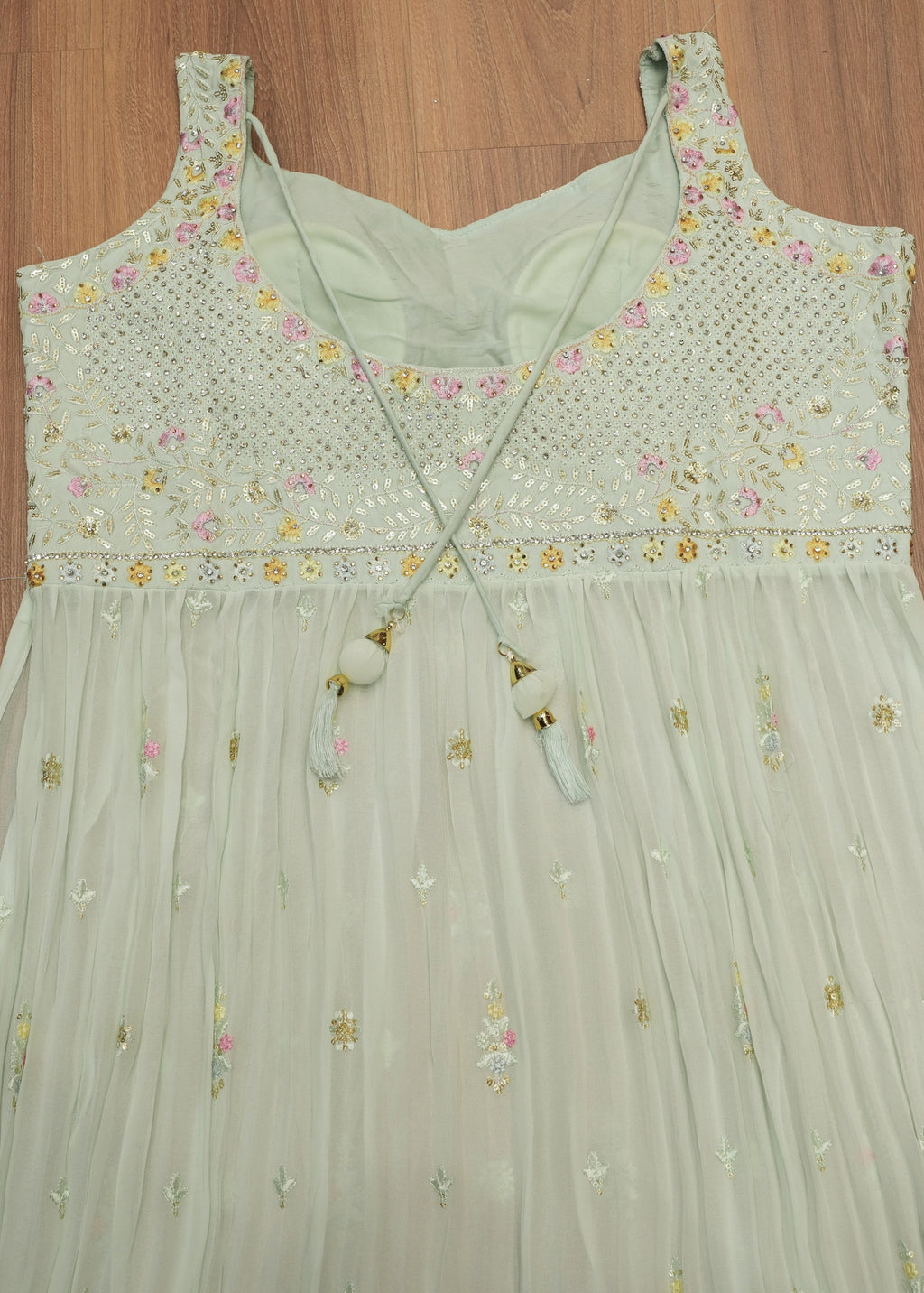 Light green dress with floral embroidery on a wooden surface