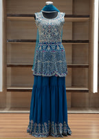 Blue dress with intricate lace detailing on a mannequin against a wooden background
