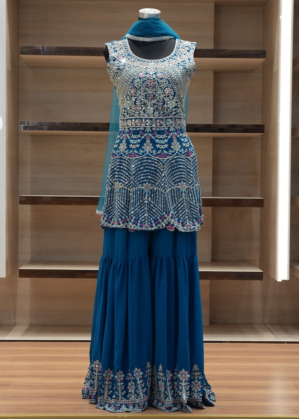 Blue embroidered outfit on a mannequin against a wooden background