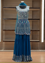 Blue embroidered outfit on a mannequin against a wooden background