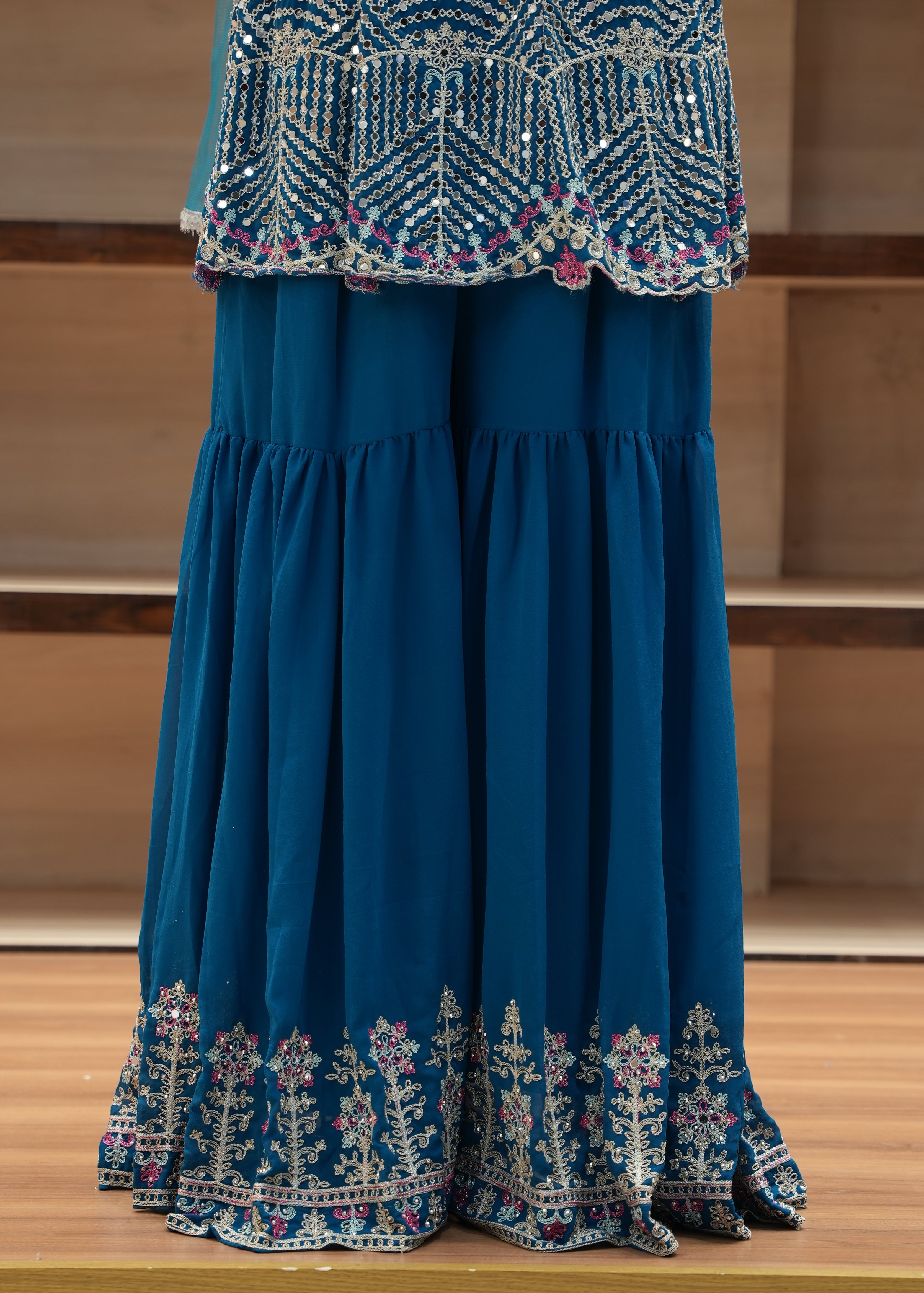 Blue embroidered fabric draped over a chair with a wooden background