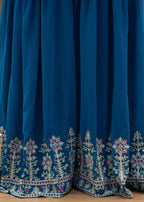 Blue dress with intricate white embroidery on a wooden surface