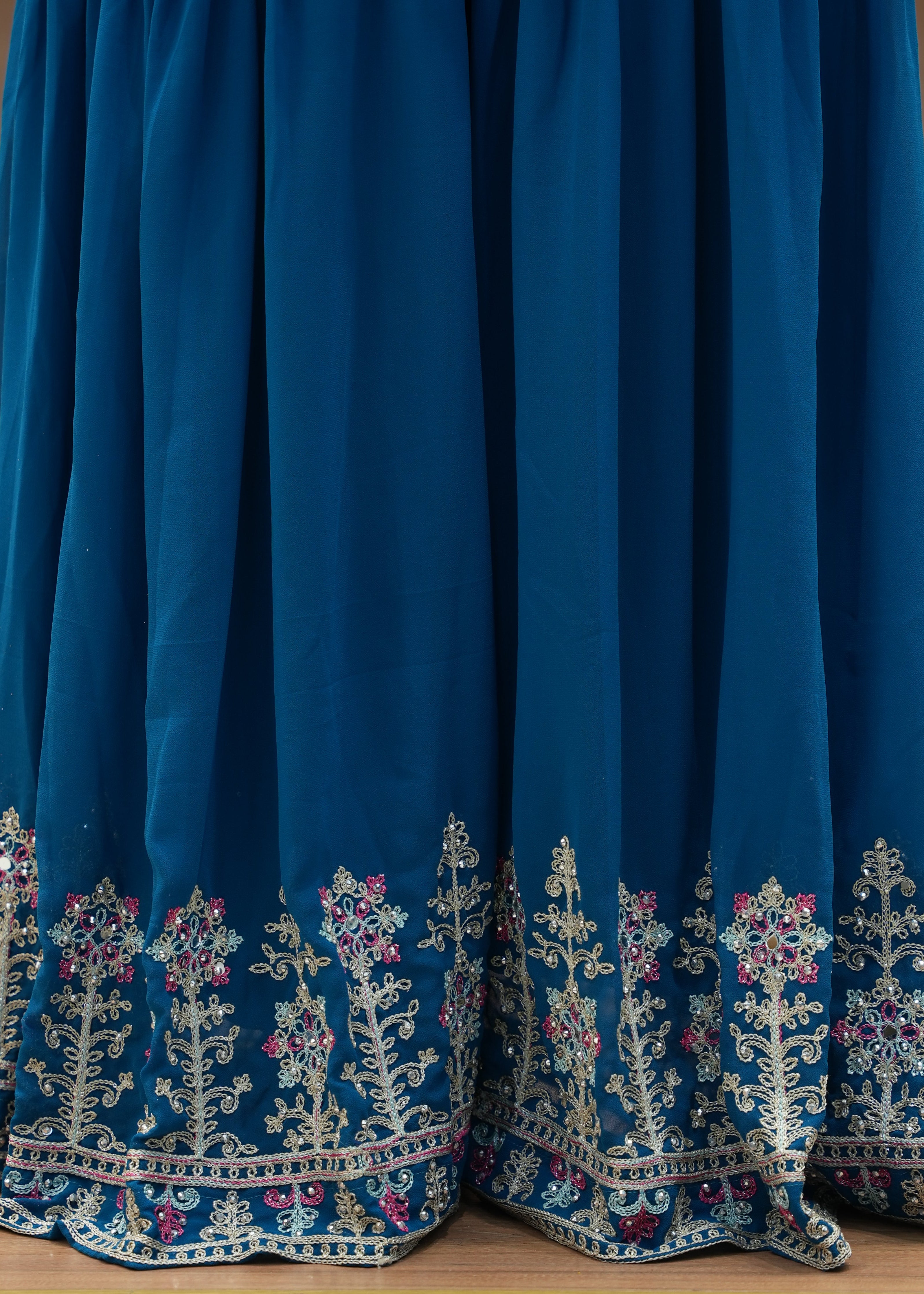 Blue dress with intricate white embroidery on a wooden surface