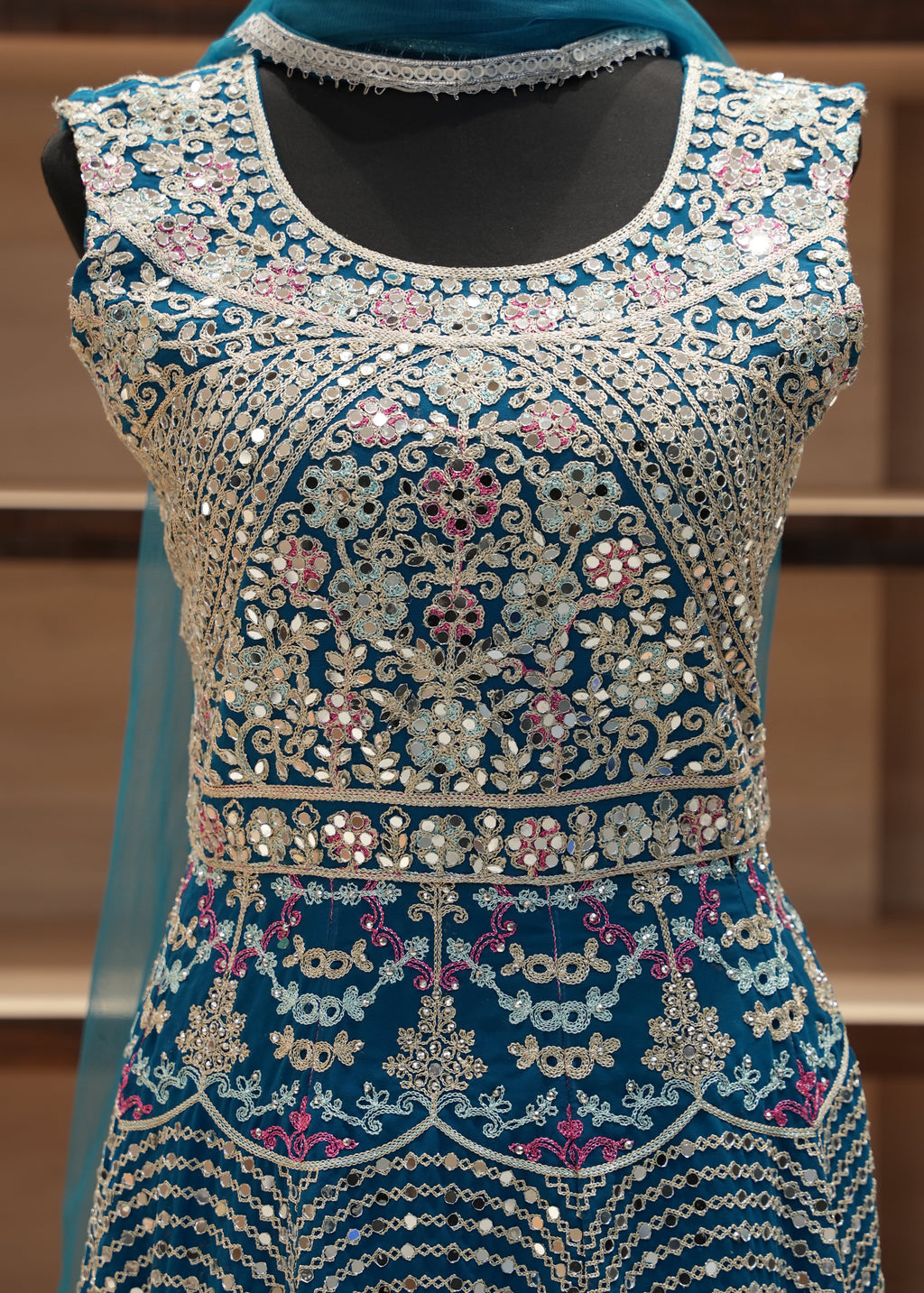 Decorative garment with intricate patterns and embellishments on a wooden stand.
