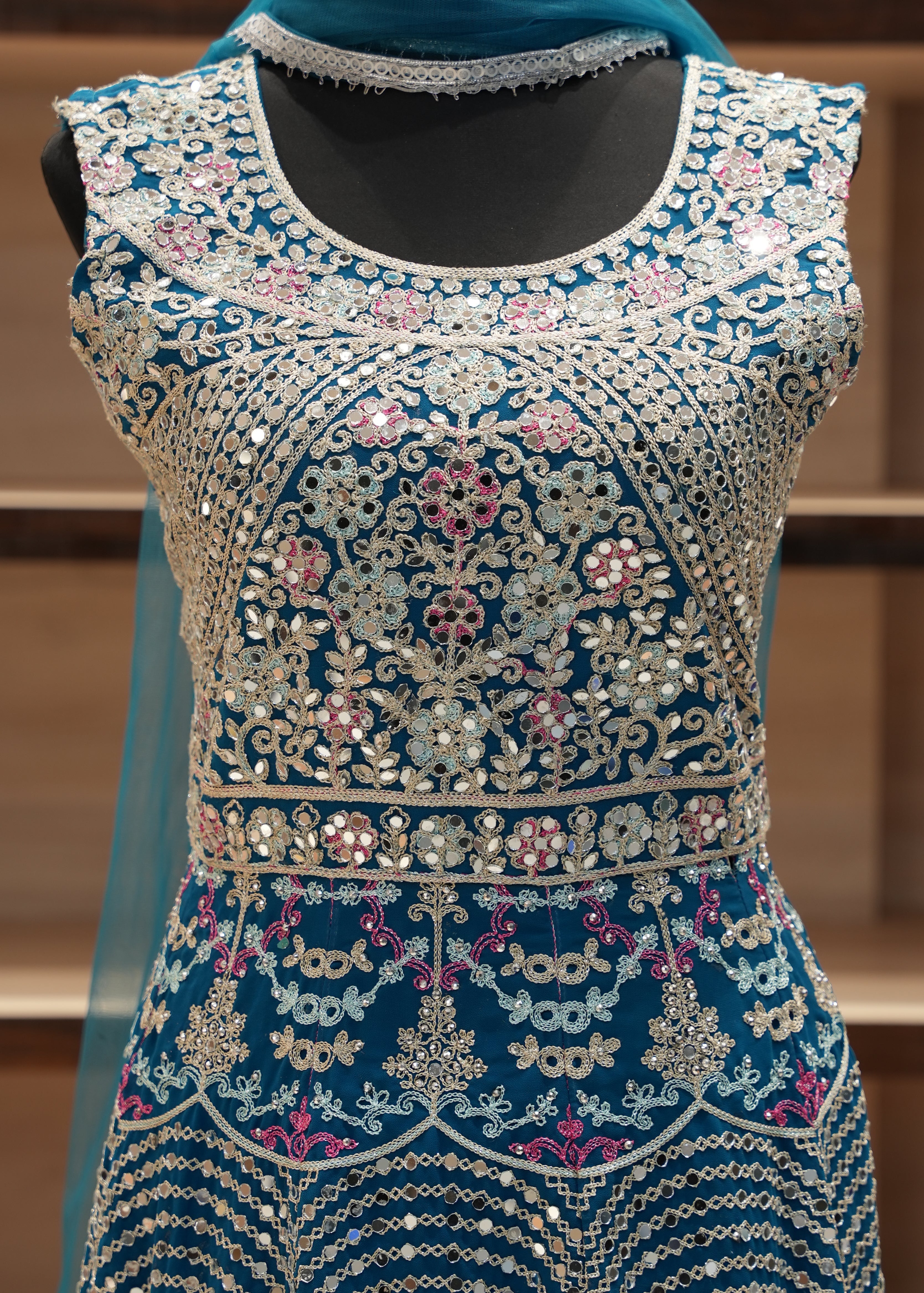 Decorative garment with intricate patterns and embellishments on a wooden stand.