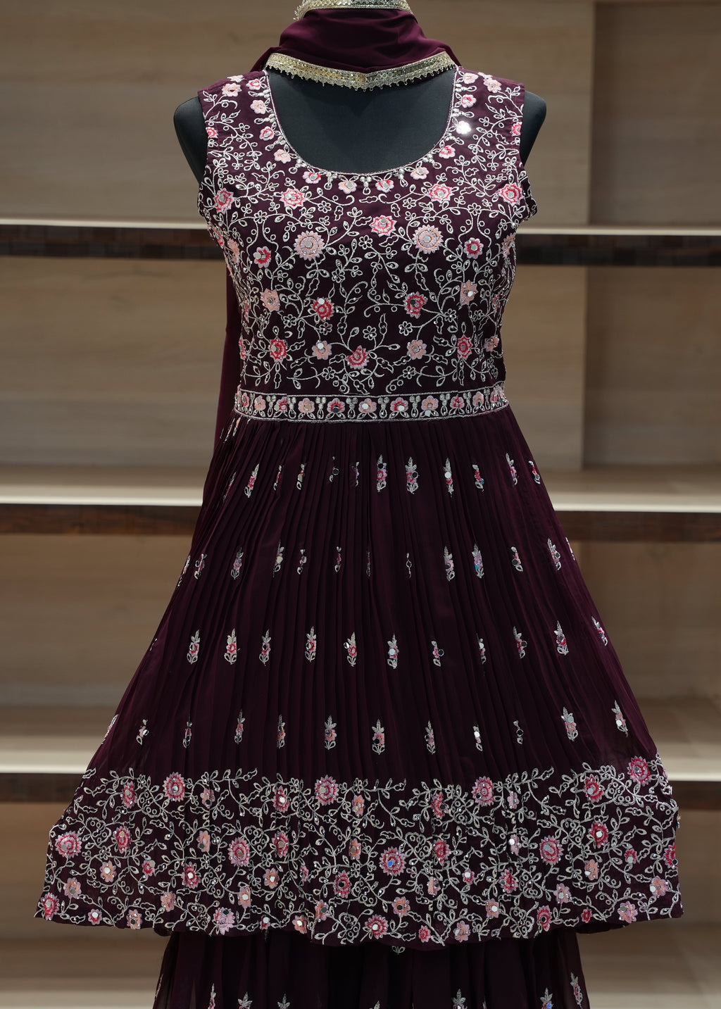 Decorative dress with floral patterns on a mannequin against a neutral background