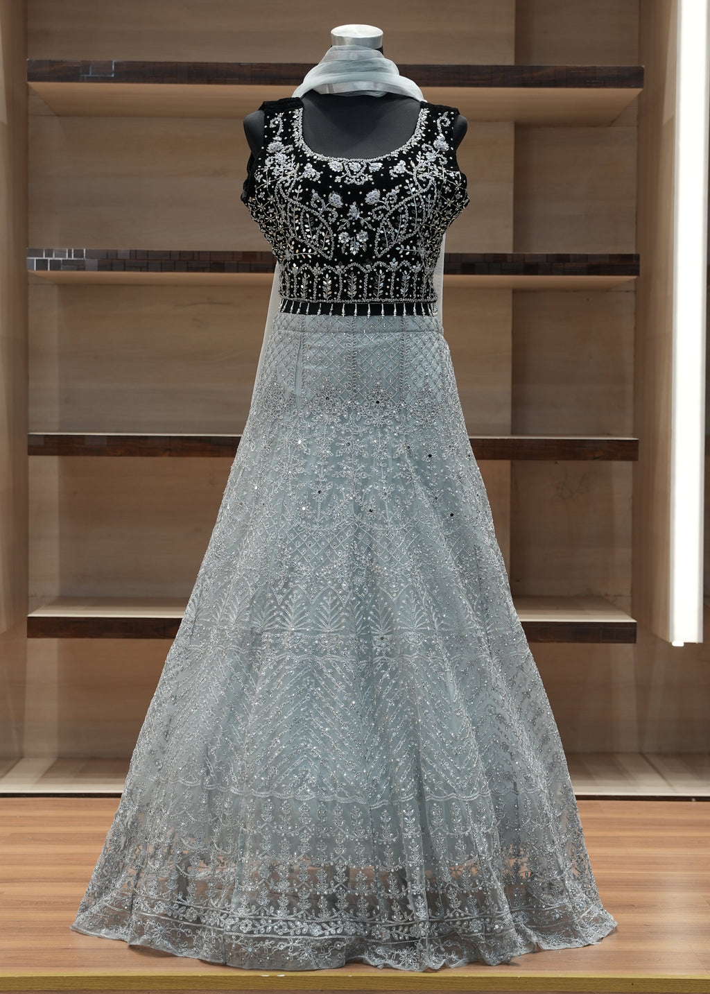 Silver evening gown with intricate detailing on a wooden shelf