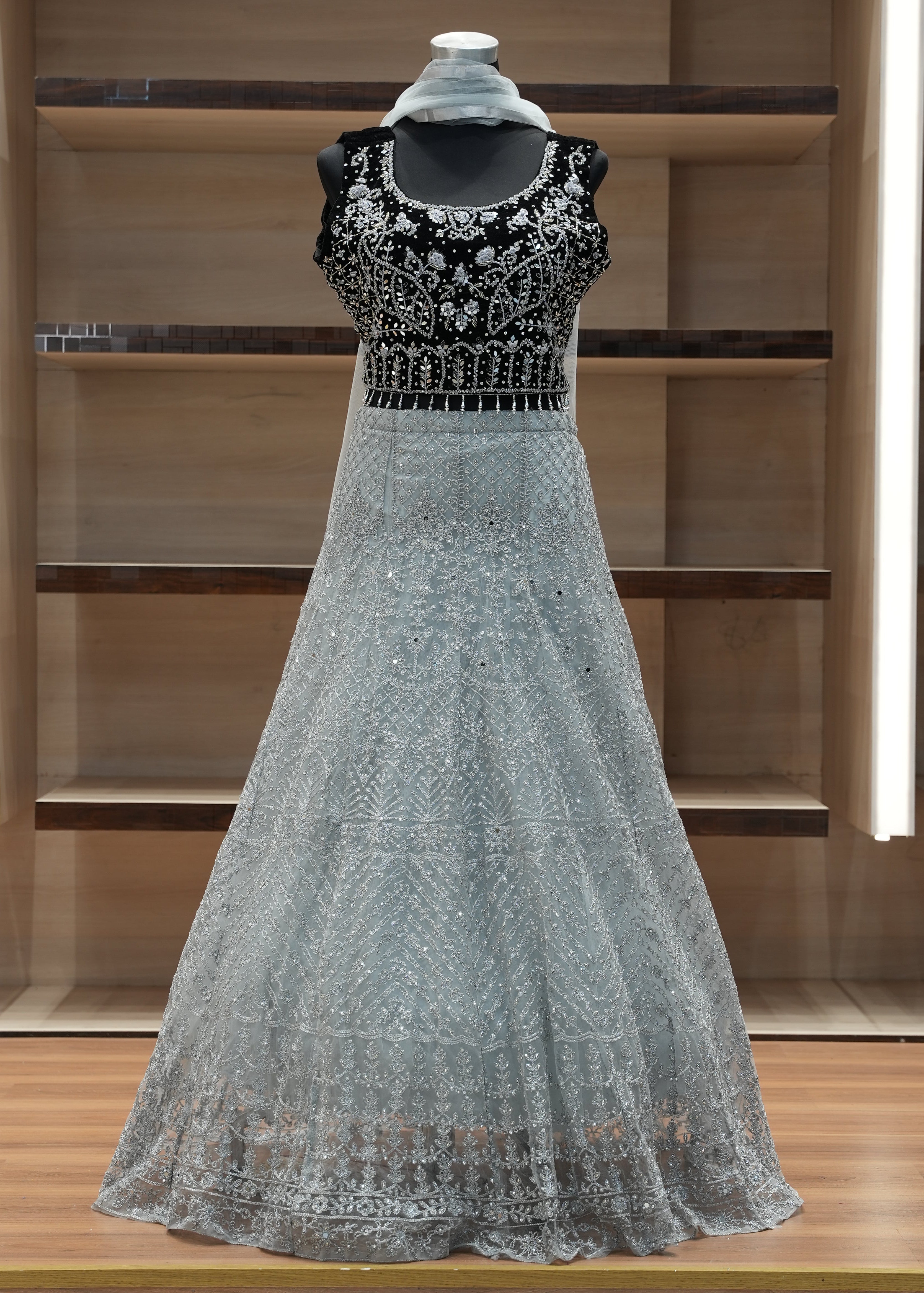 Silver evening gown with intricate detailing on a wooden shelf