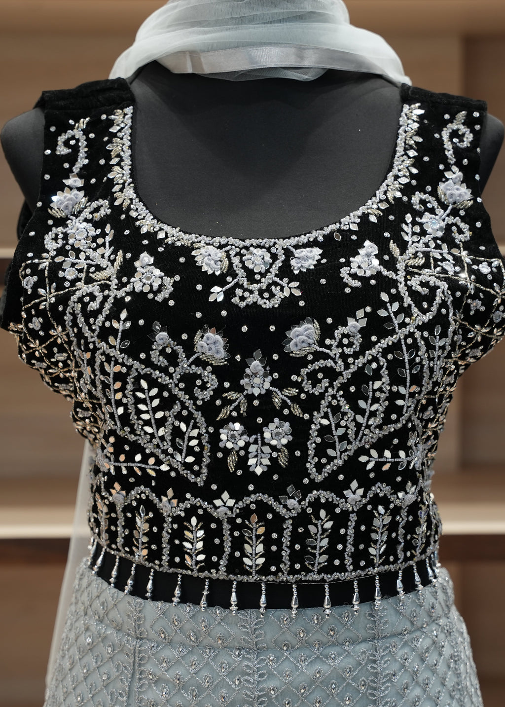 Black embroidered top on a mannequin with a blurred background