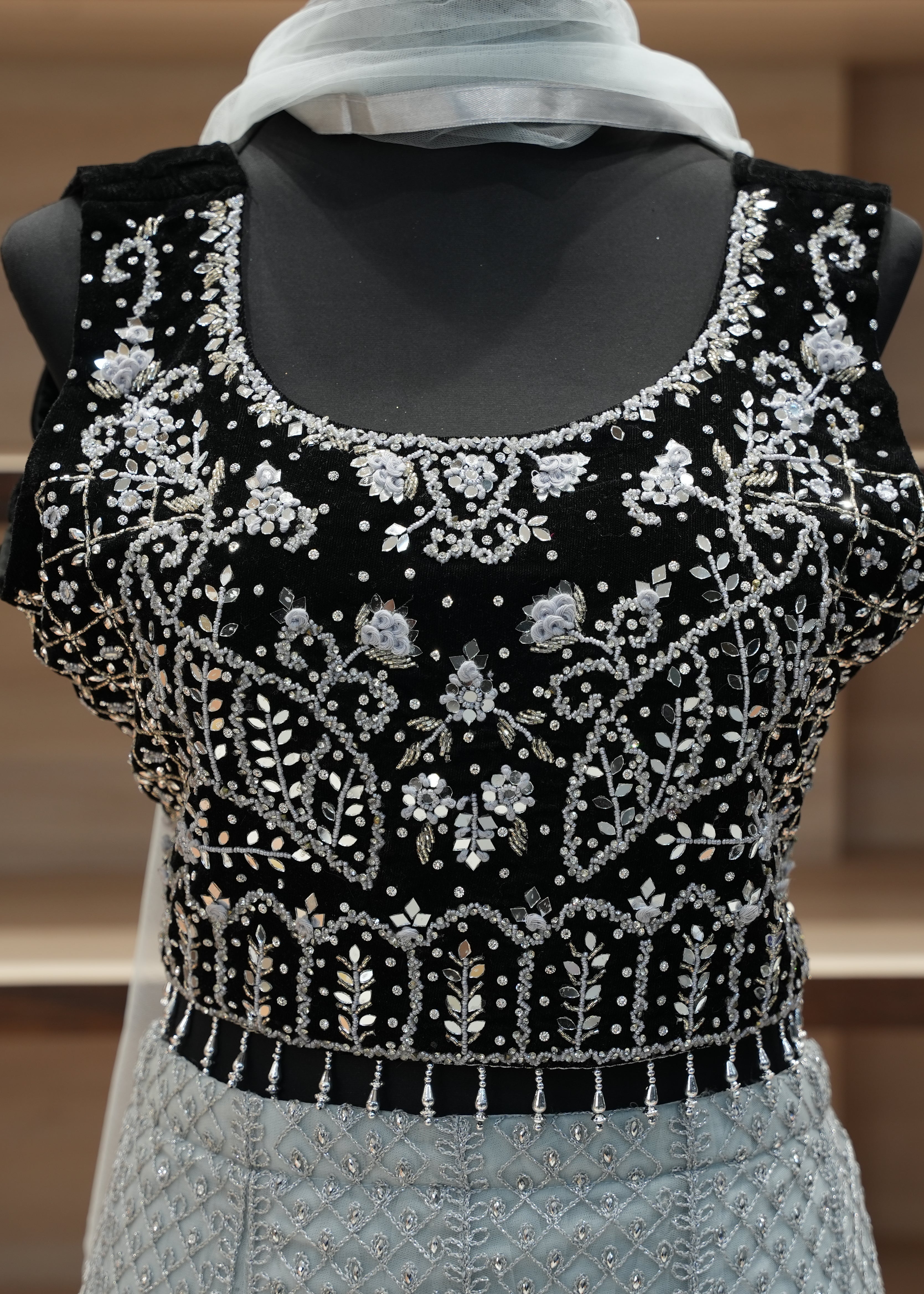Black embroidered top on a mannequin with a blurred background