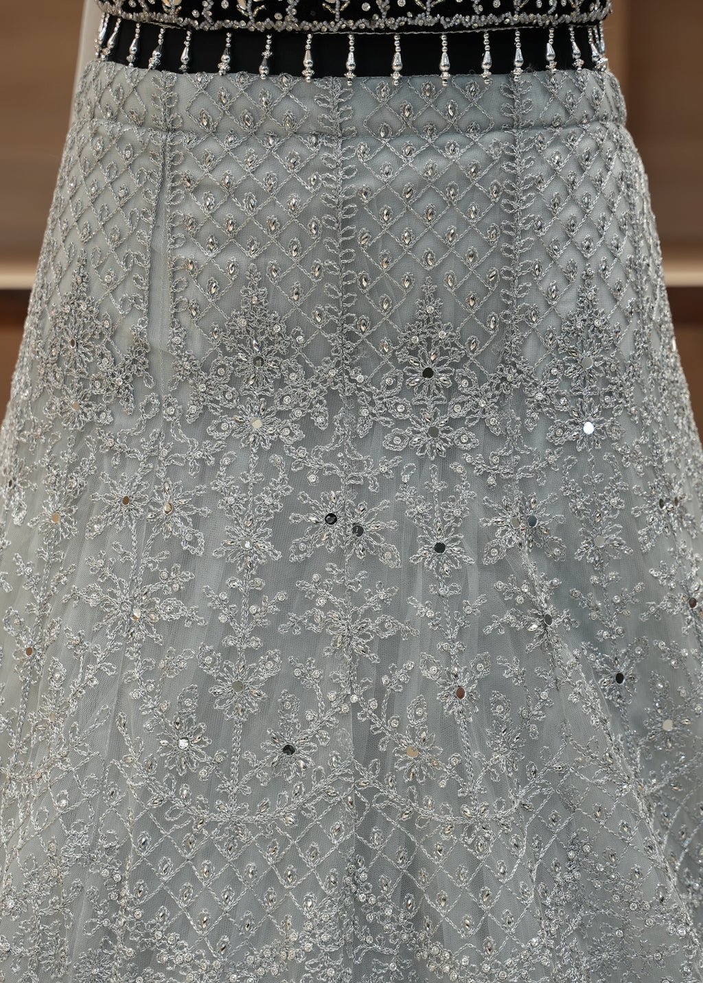 Close-up of a gray embroidered fabric with black accents on a wooden surface