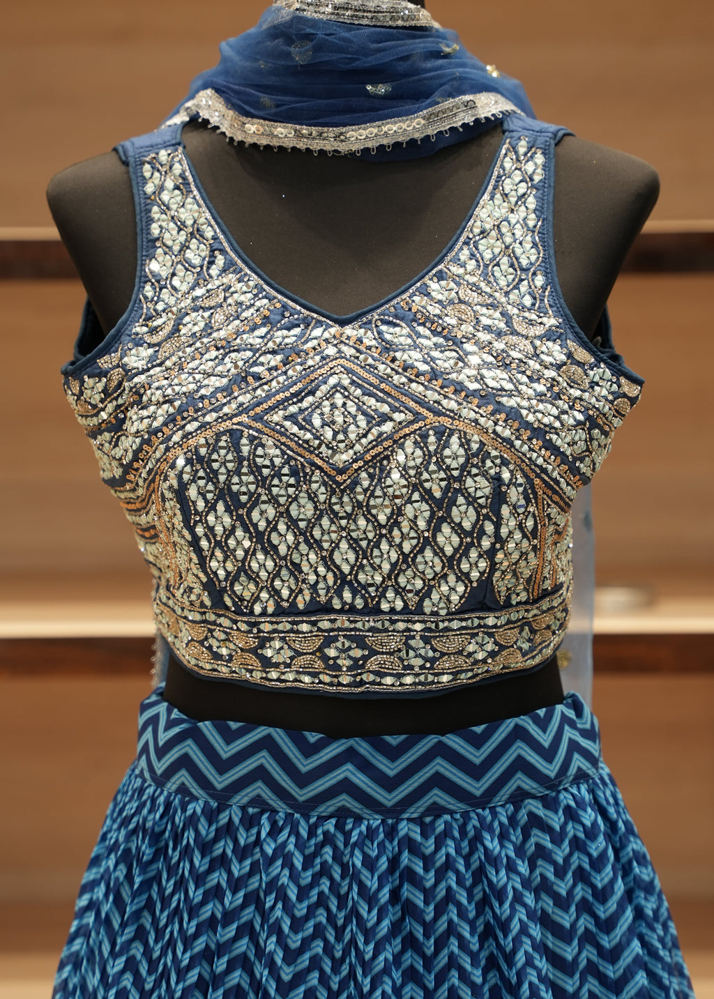 Blue and patterned top on a mannequin against a wooden background