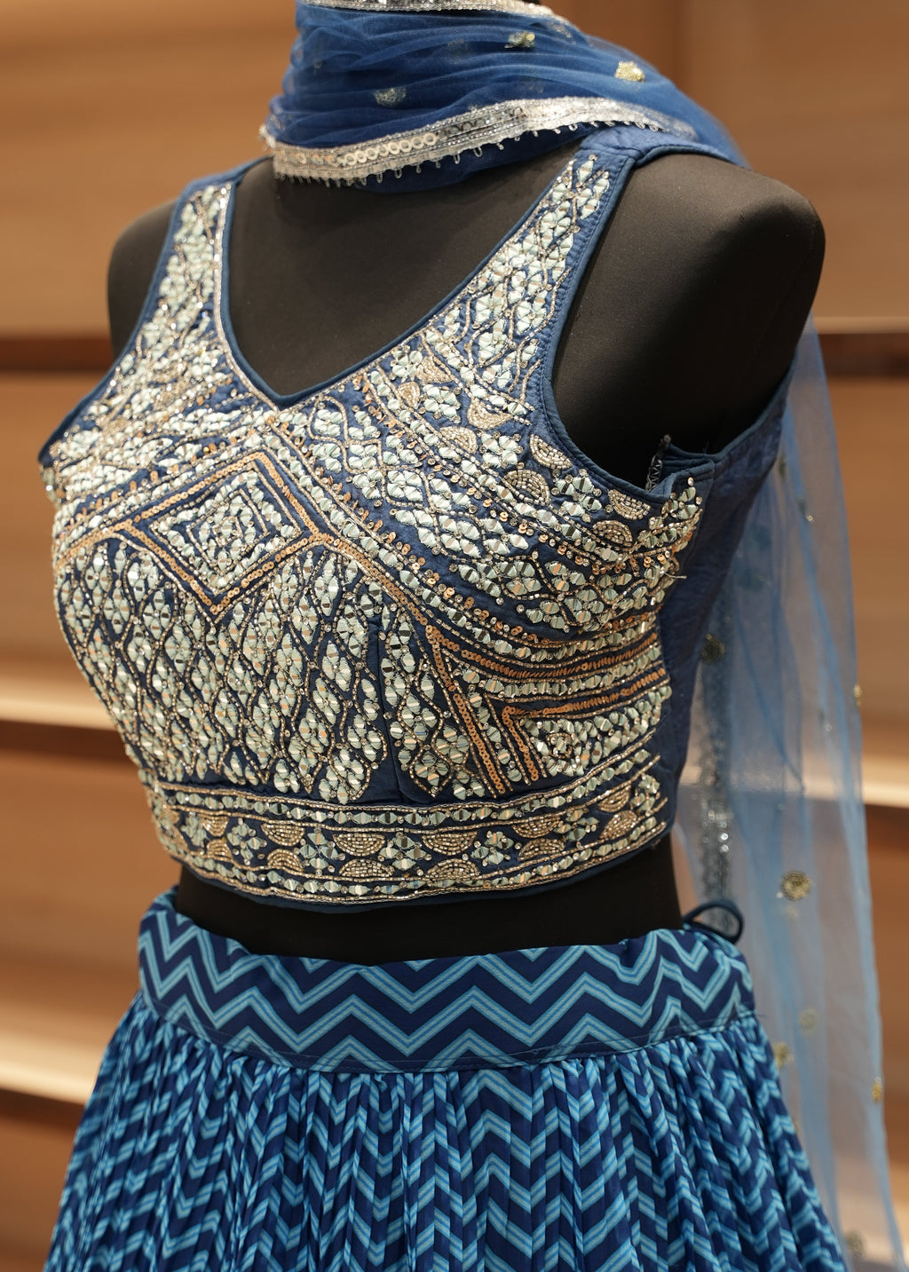 Decorative fabric with intricate patterns on a mannequin against a wooden background