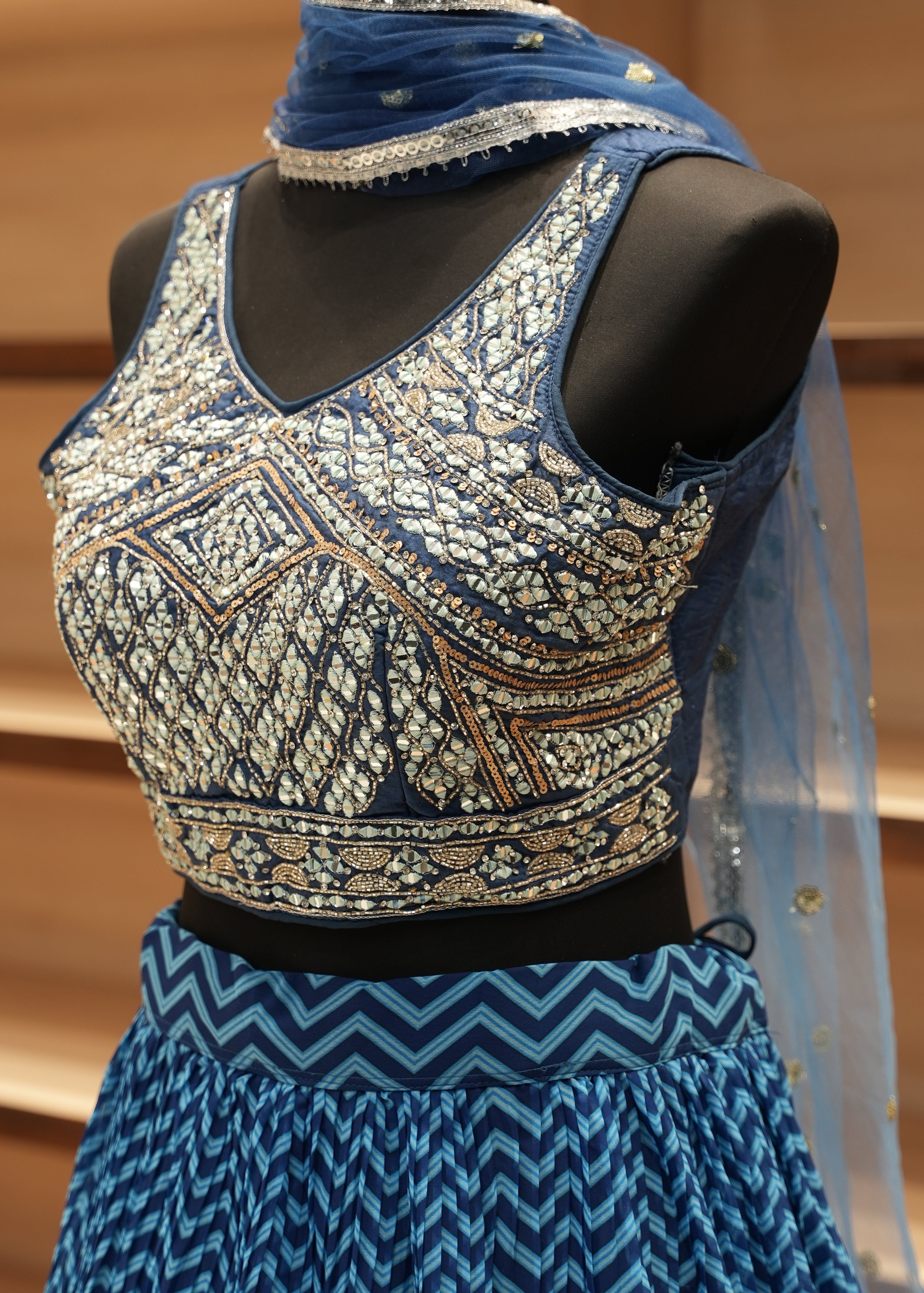 Decorative fabric with intricate patterns on a mannequin against a wooden background