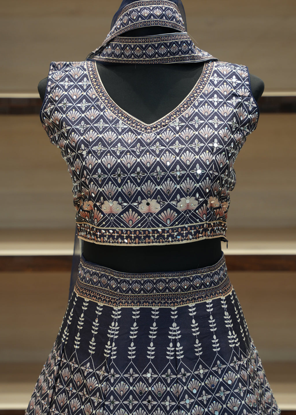 Decorative blue garment with intricate patterns on a mannequin against a neutral background