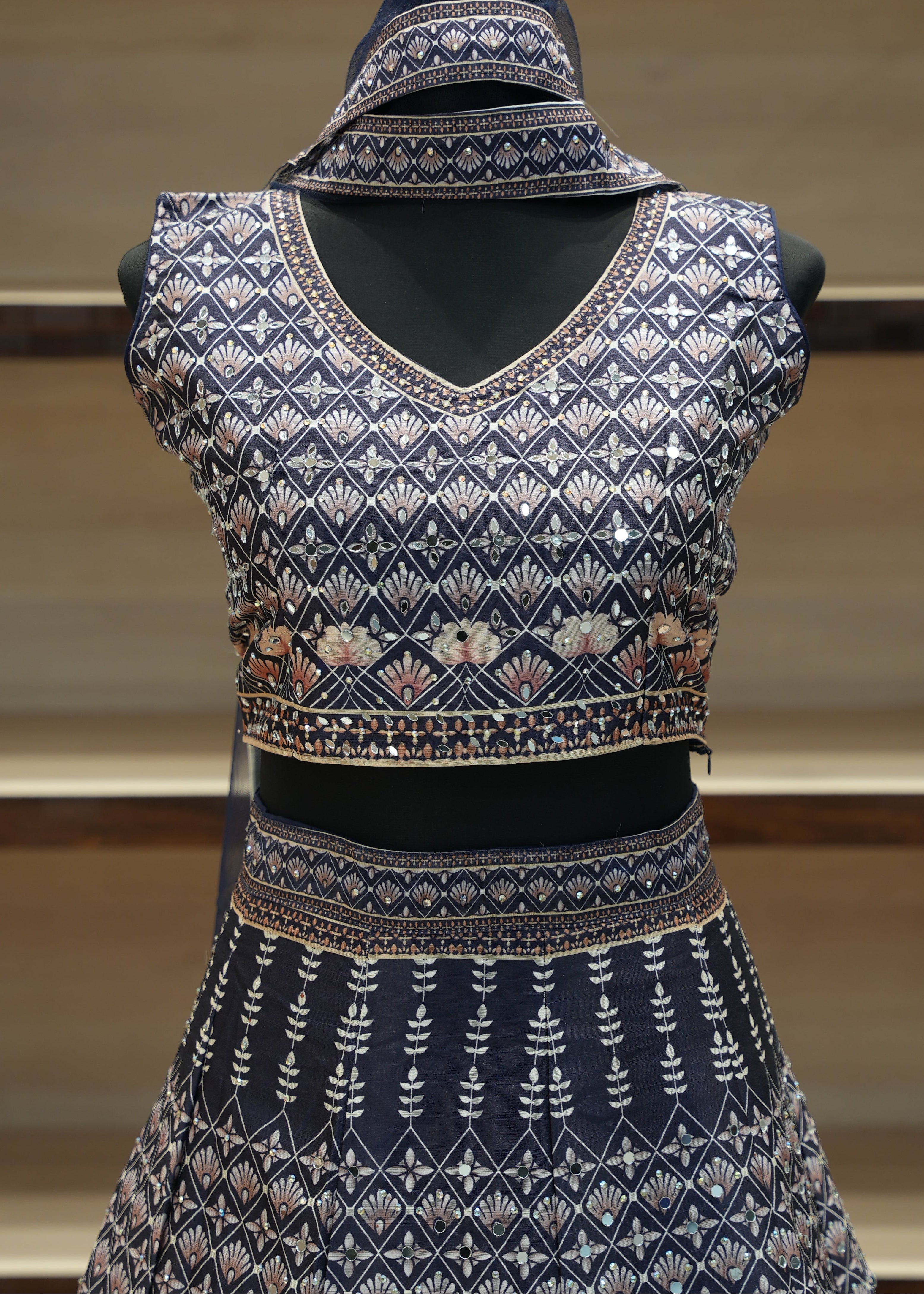 Decorative blue garment with intricate patterns on a mannequin against a neutral background