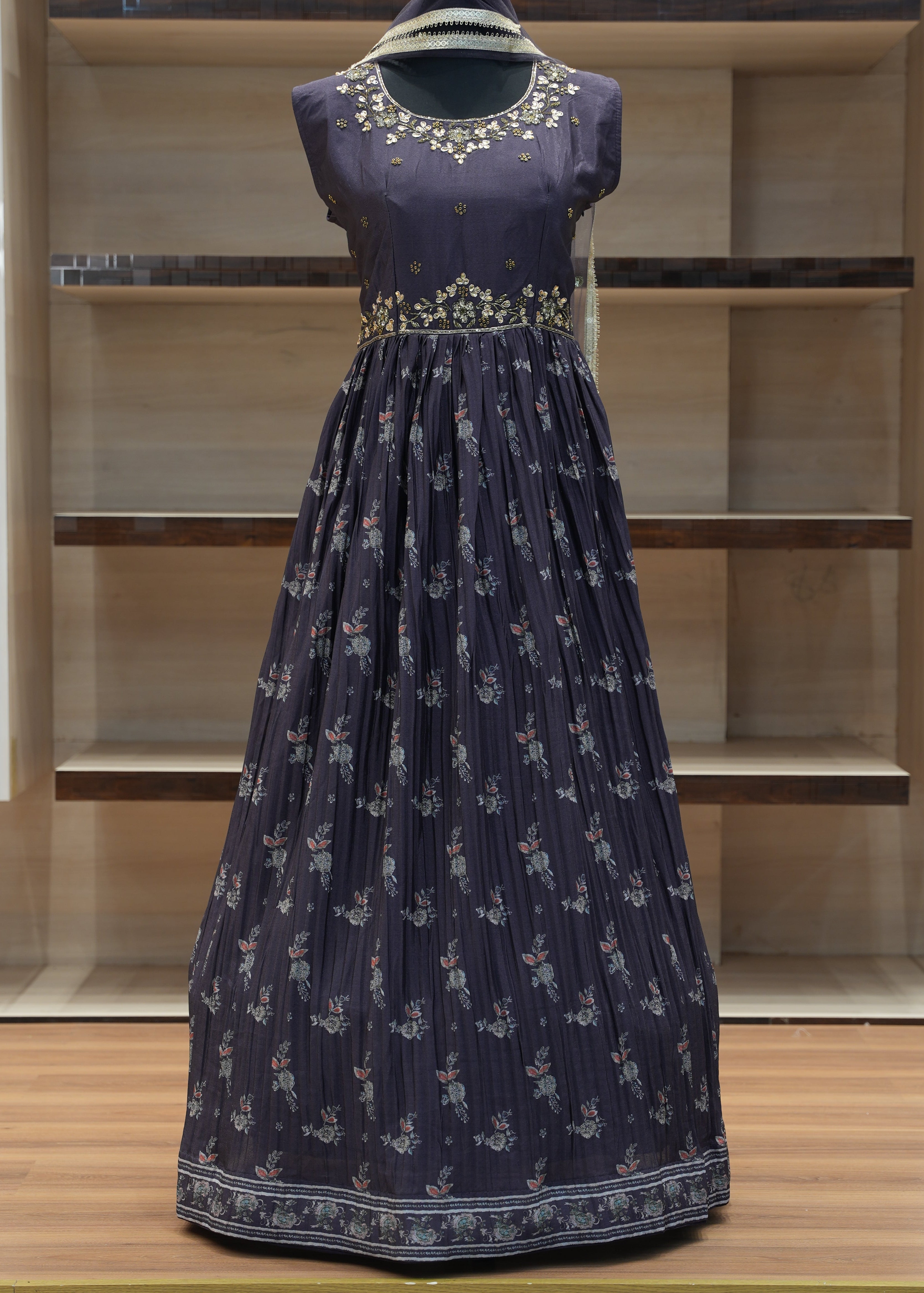 Navy blue dress with white floral pattern on a mannequin against a wooden panel background