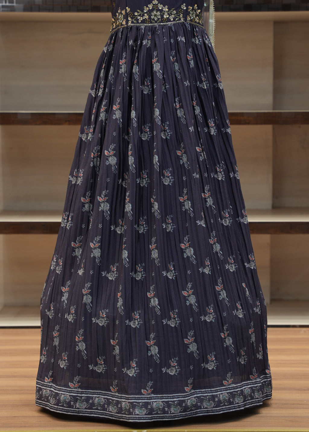 Navy blue pleated skirt with floral pattern on a wooden chair.