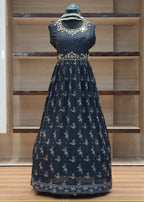 Navy blue dress with white floral patterns on a mannequin against a wooden panel background