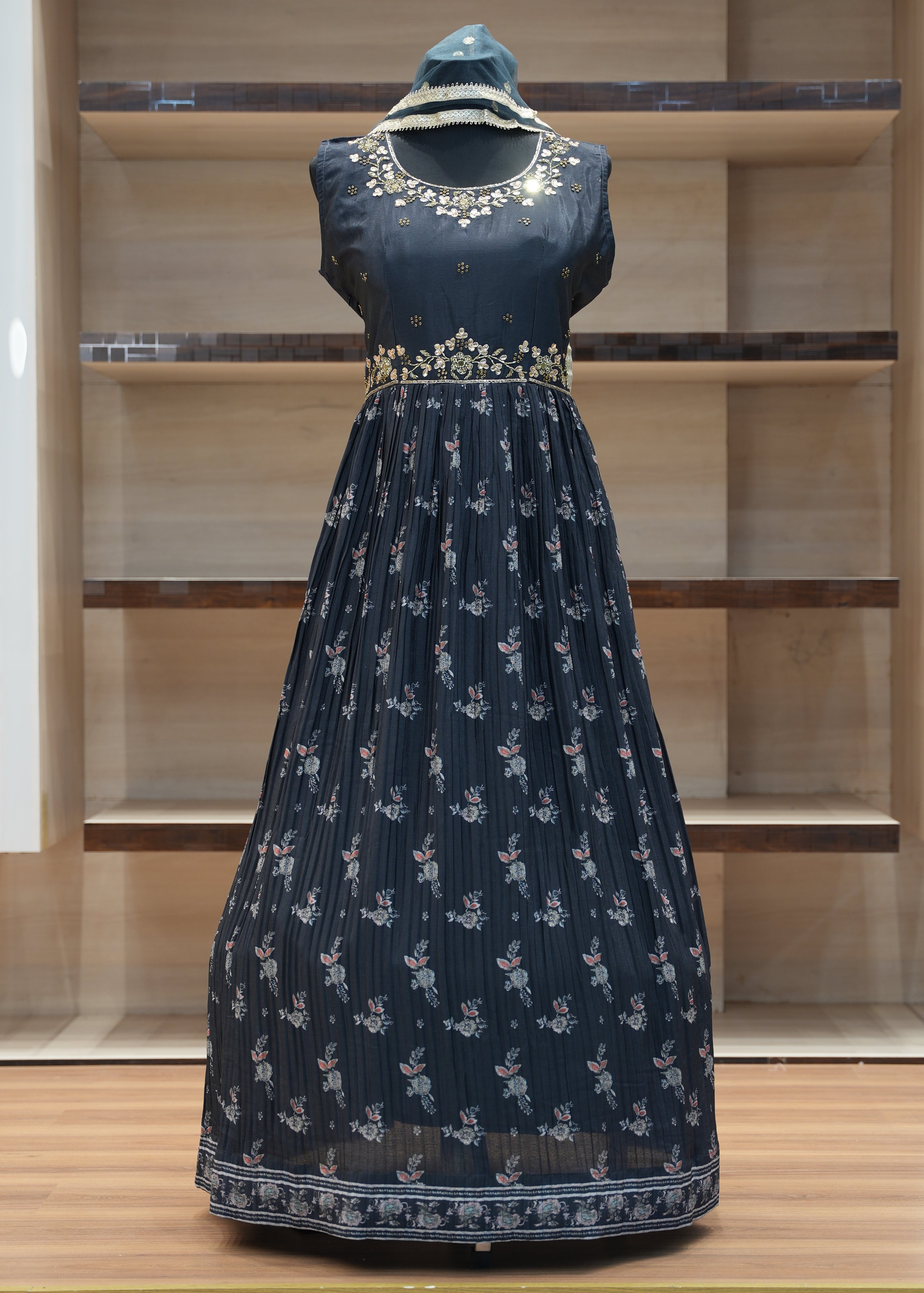 Navy blue dress with white floral patterns on a mannequin against a wooden panel background