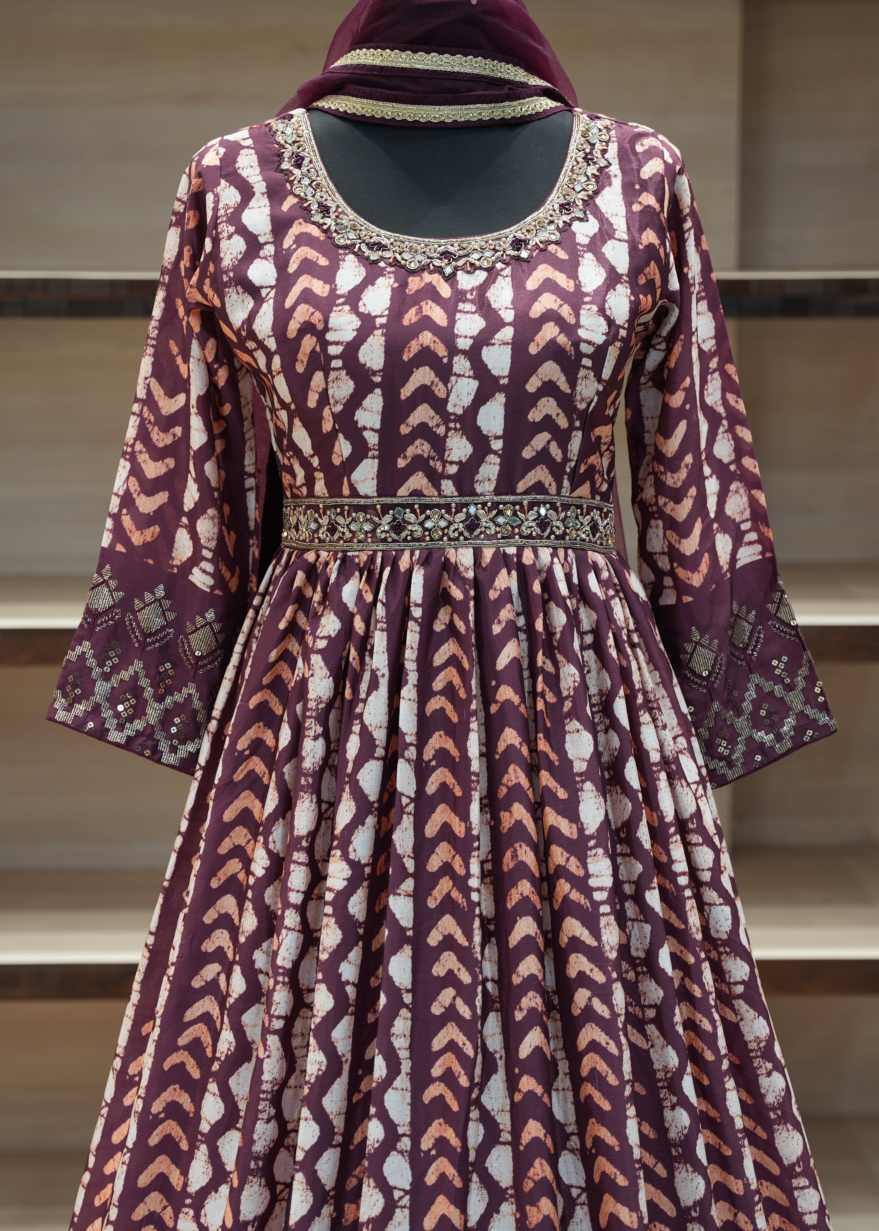 Patterned dress with a hood on a mannequin against a neutral background