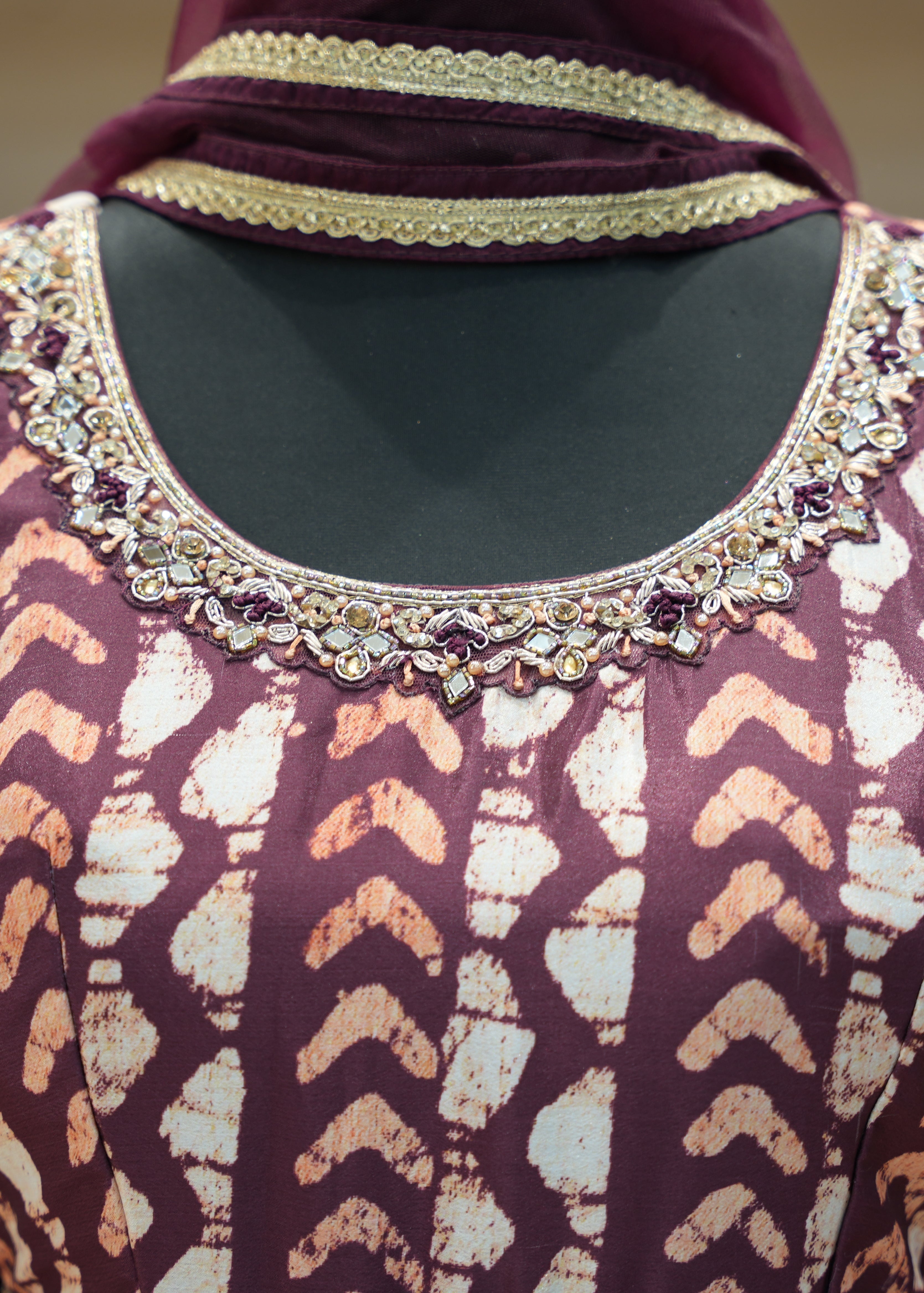 Close-up of a patterned garment with intricate embellishments on a blurred background