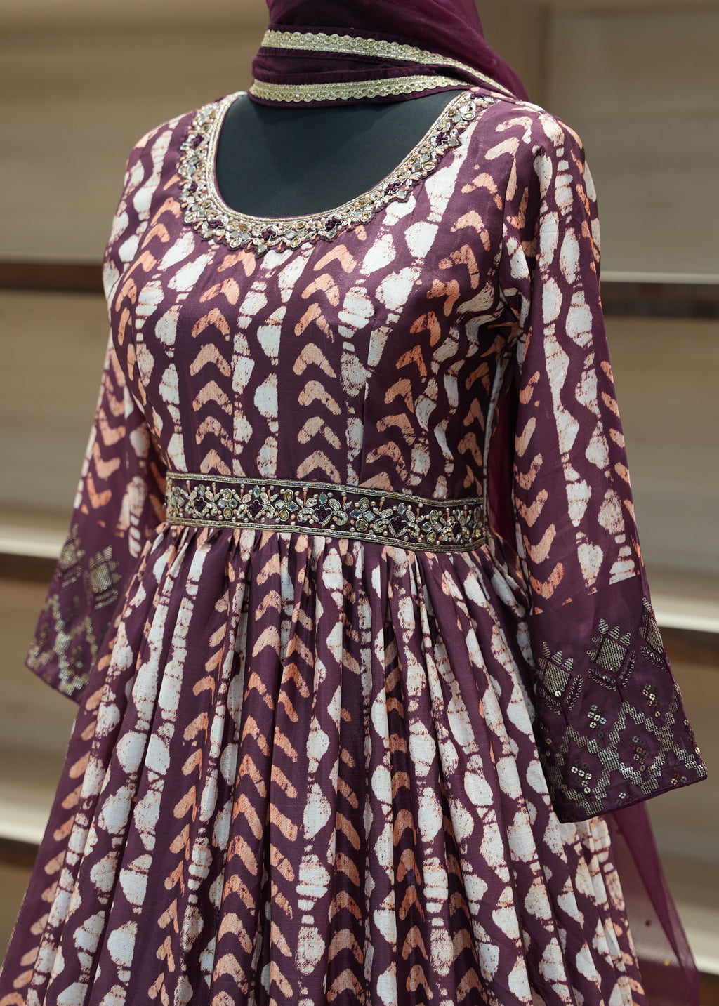 Purple patterned garment with intricate detailing on a mannequin against a neutral background