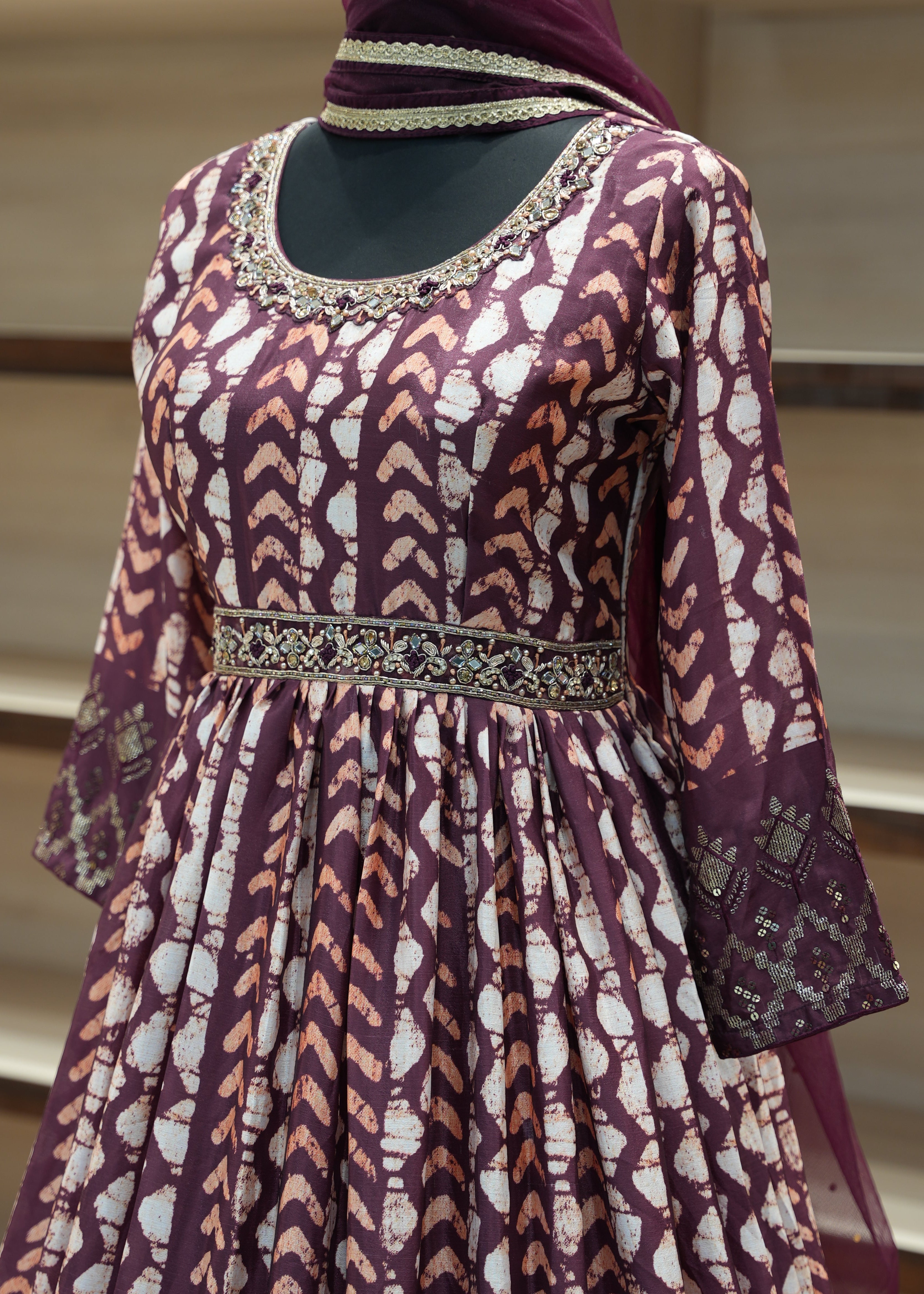 Purple patterned garment with intricate detailing on a mannequin against a neutral background