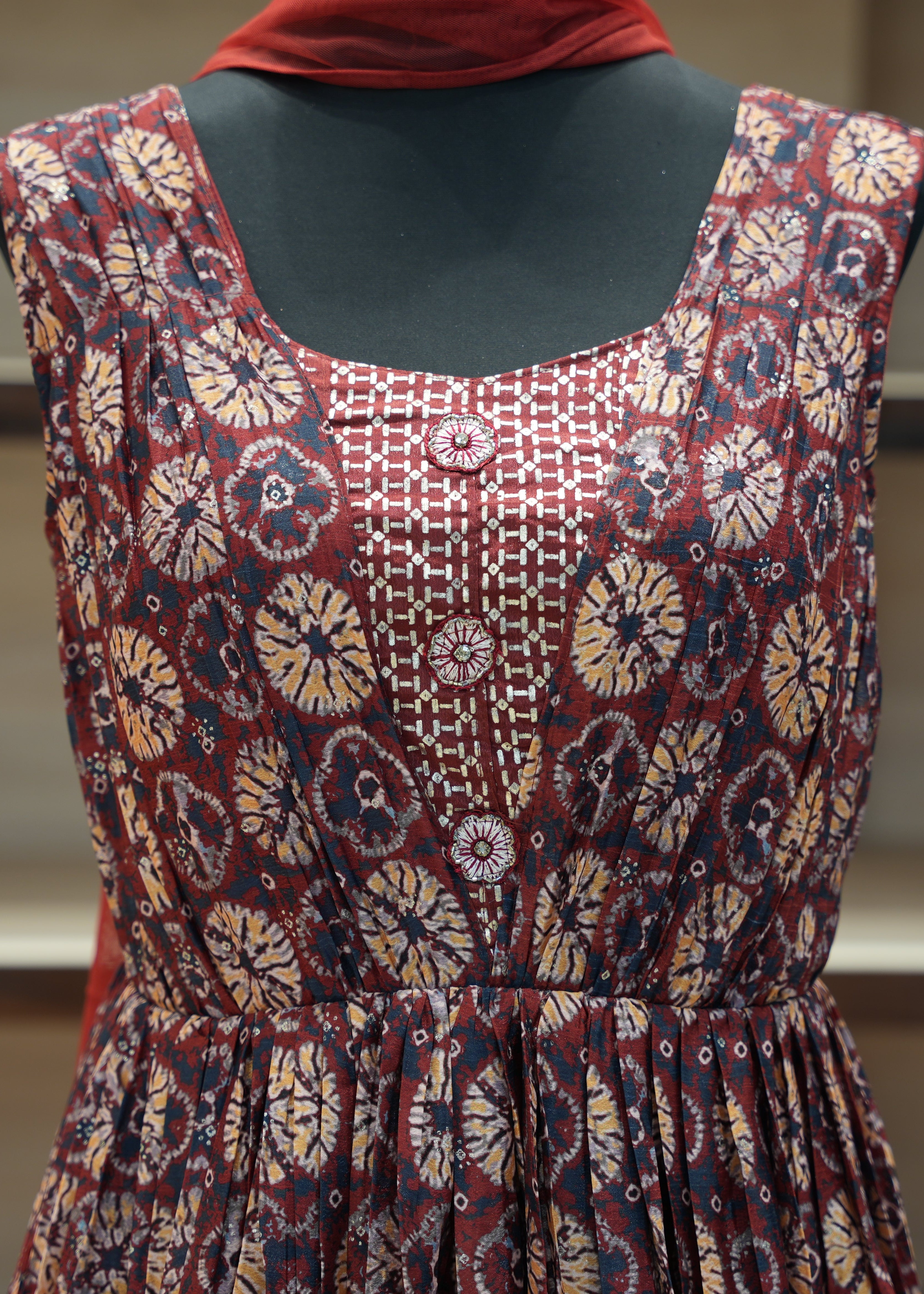 Mannequin wearing a patterned dress with a red headscarf on a blurred background