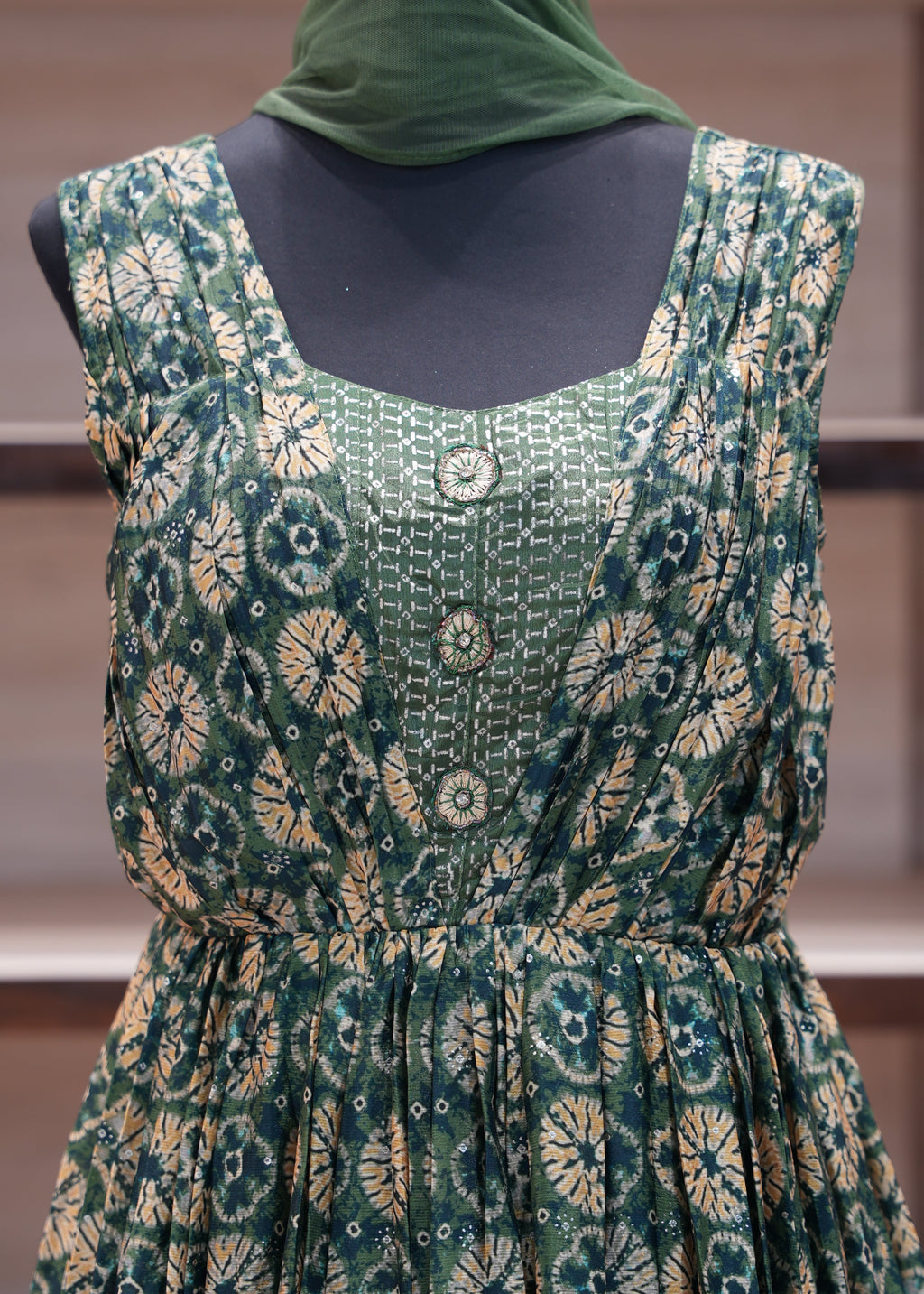 Green patterned dress on a mannequin against a neutral background