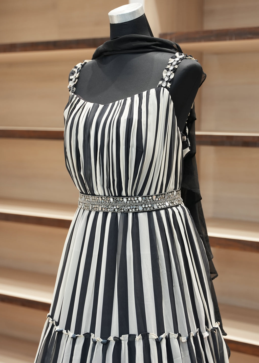Black and white striped dress with decorative elements on a wooden rack.