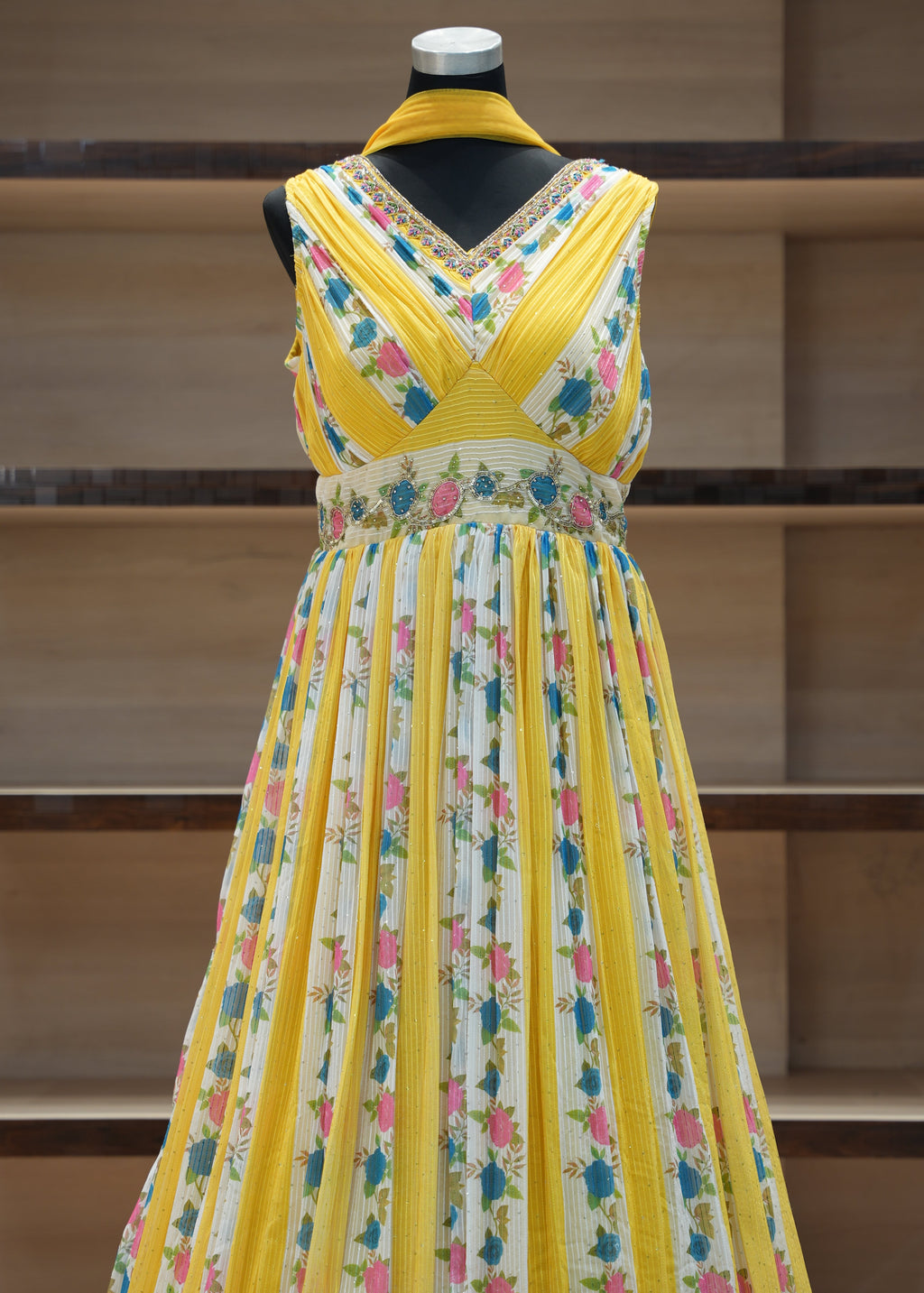 Colorful dress with floral pattern on a mannequin against a wooden background