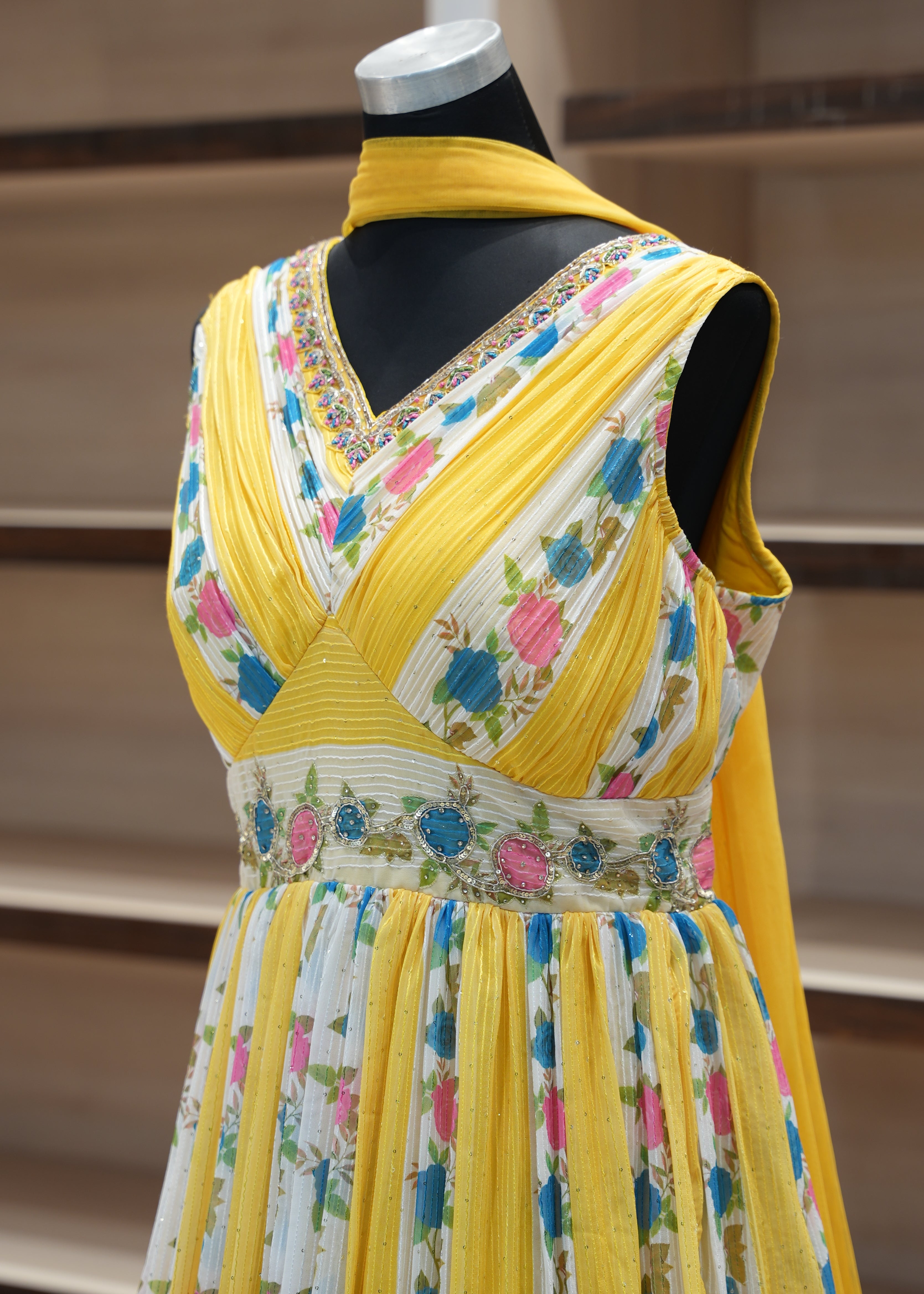 Colorful floral-patterned dress with yellow trim on a mannequin against a neutral background