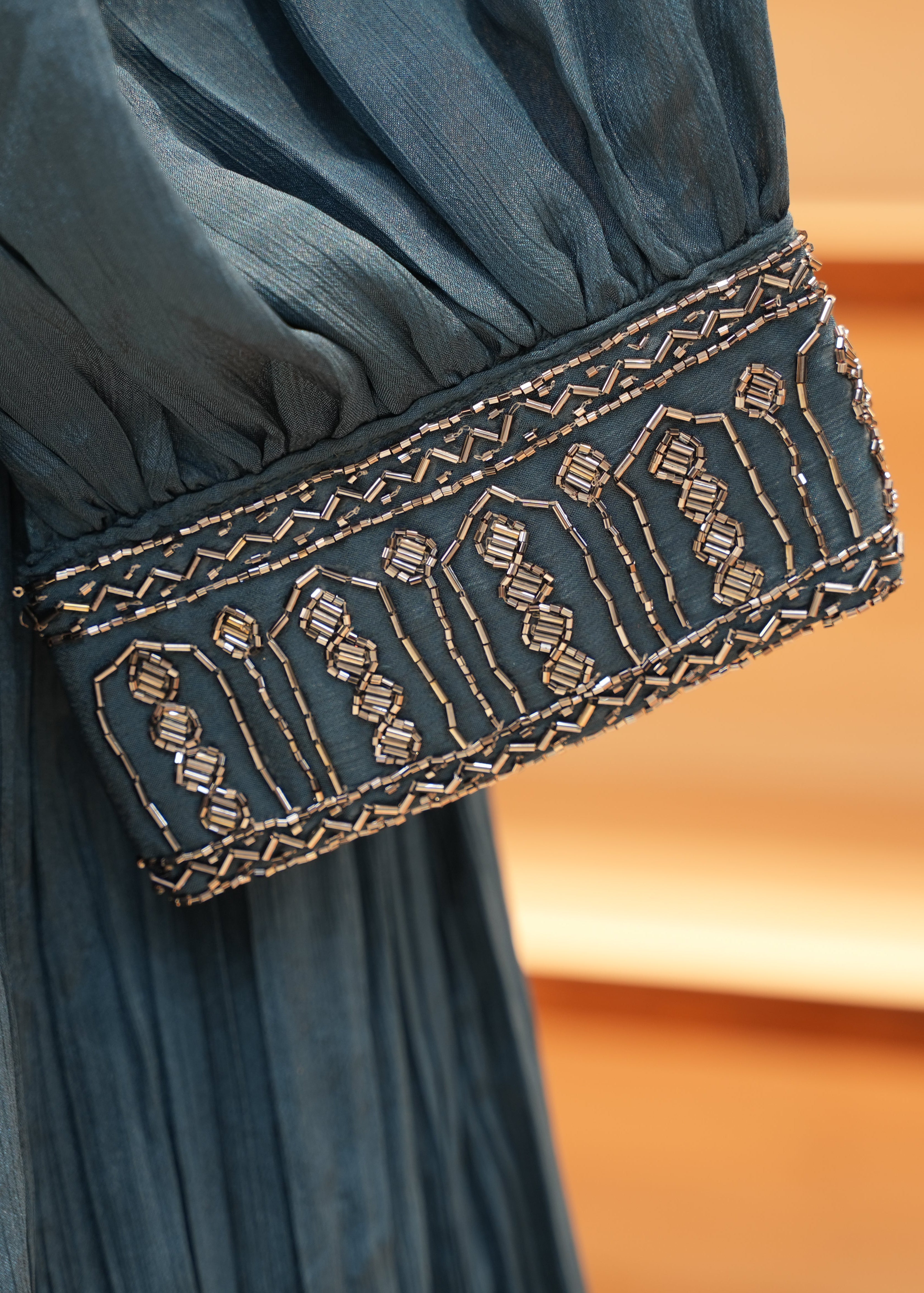 Close-up of a blue garment with intricate gold embroidery on a blurred background