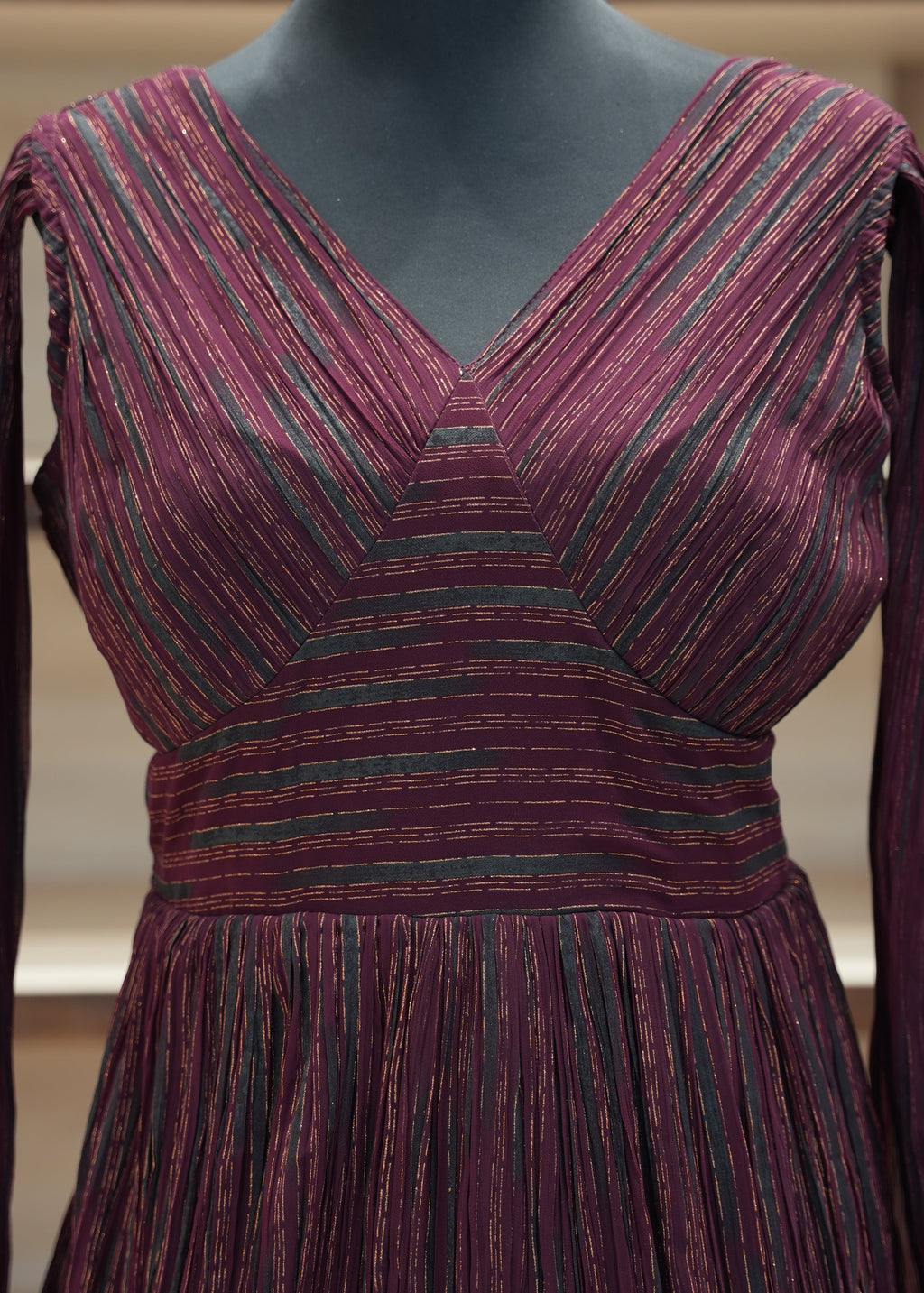 Close-up of a burgundy and green striped dress on a mannequin.
