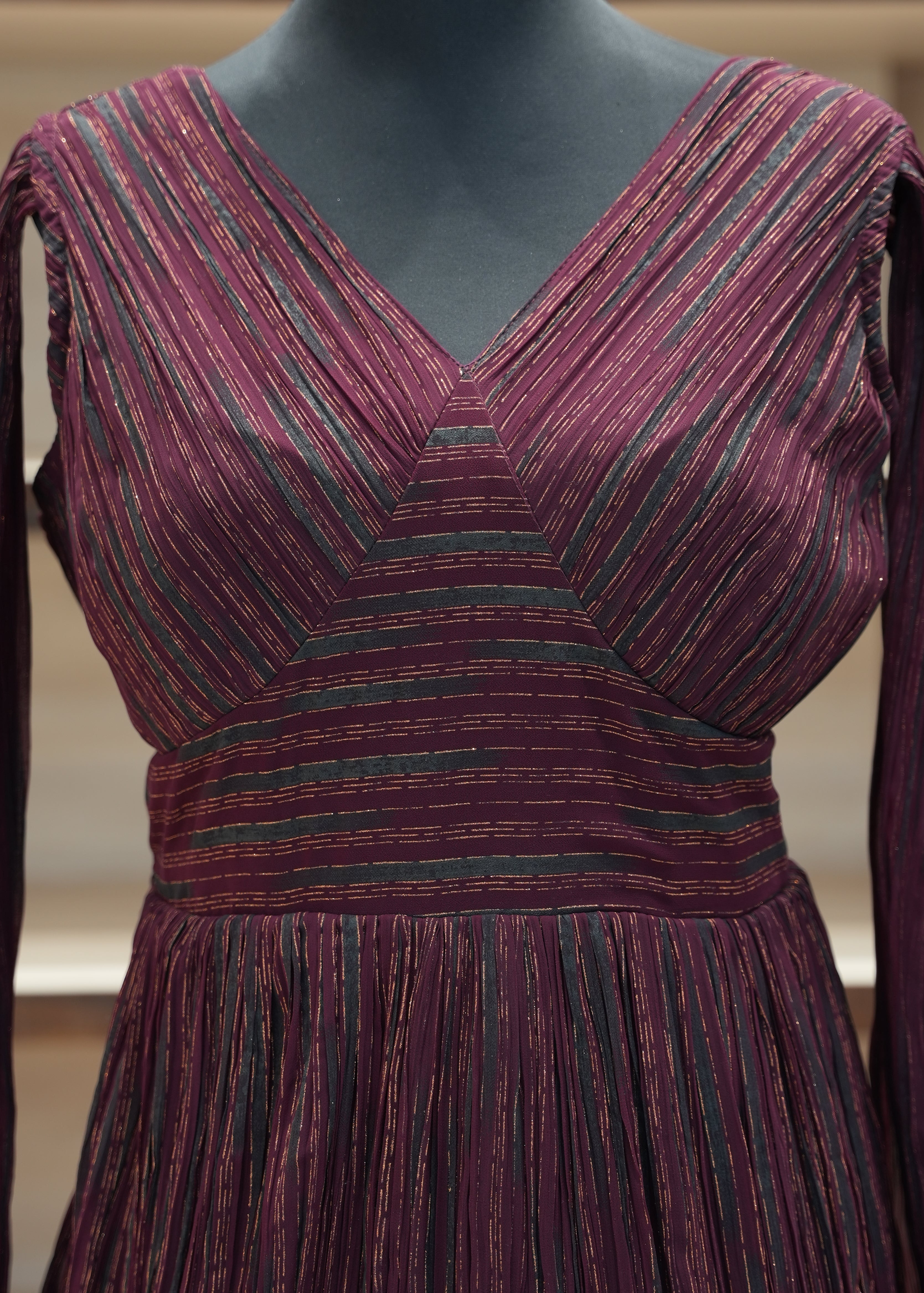 Close-up of a burgundy and green striped dress on a mannequin.