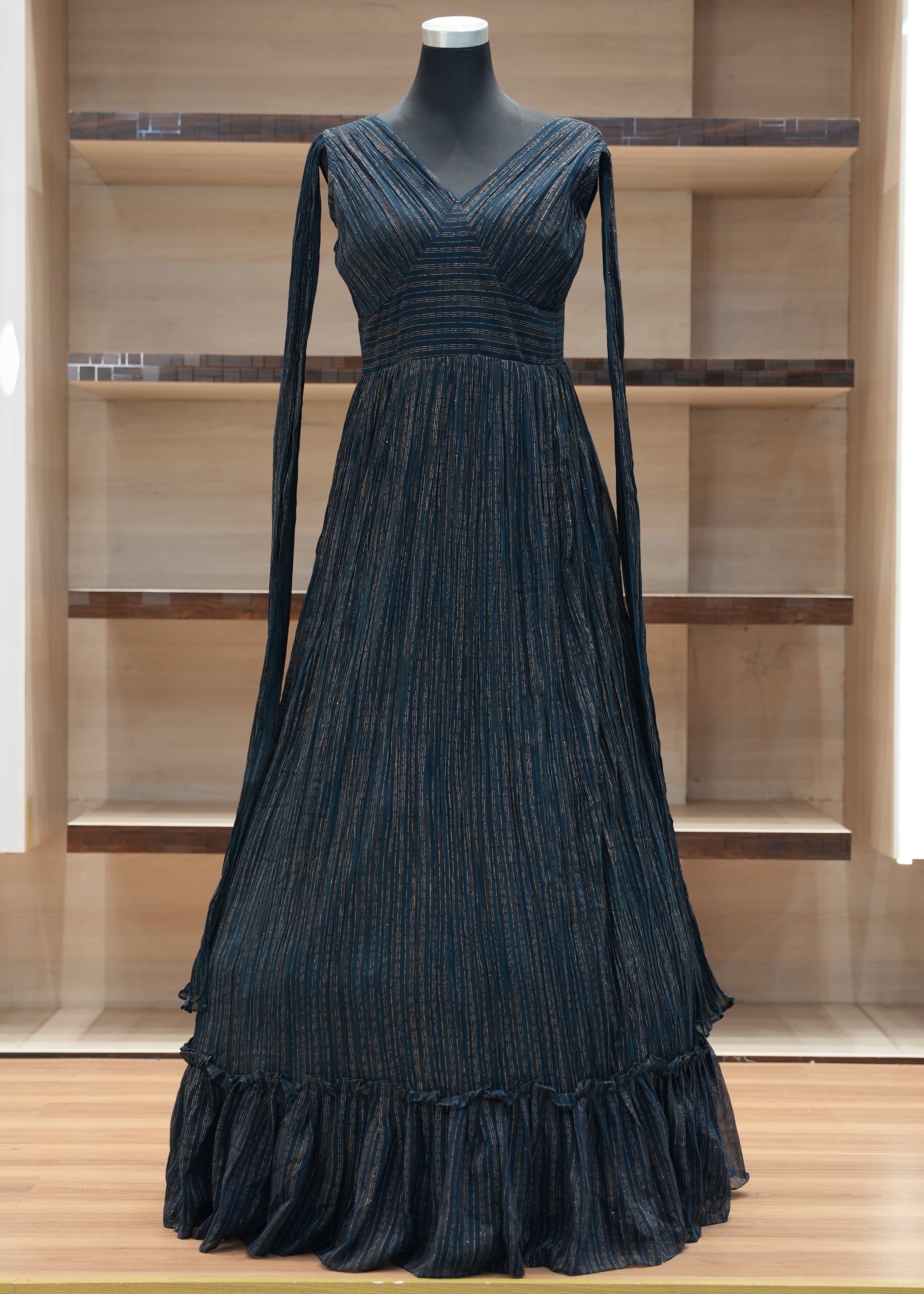 Black evening gown on a mannequin against a wooden panel background