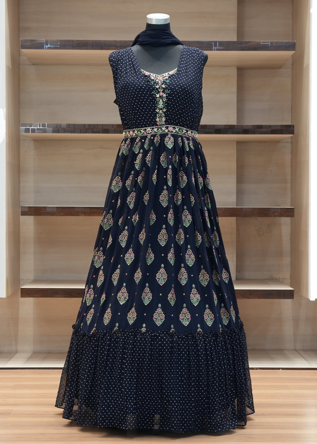 Navy blue embroidered dress on a mannequin against a wooden shelf background