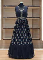 Navy blue embroidered dress on a mannequin against a wooden shelf background