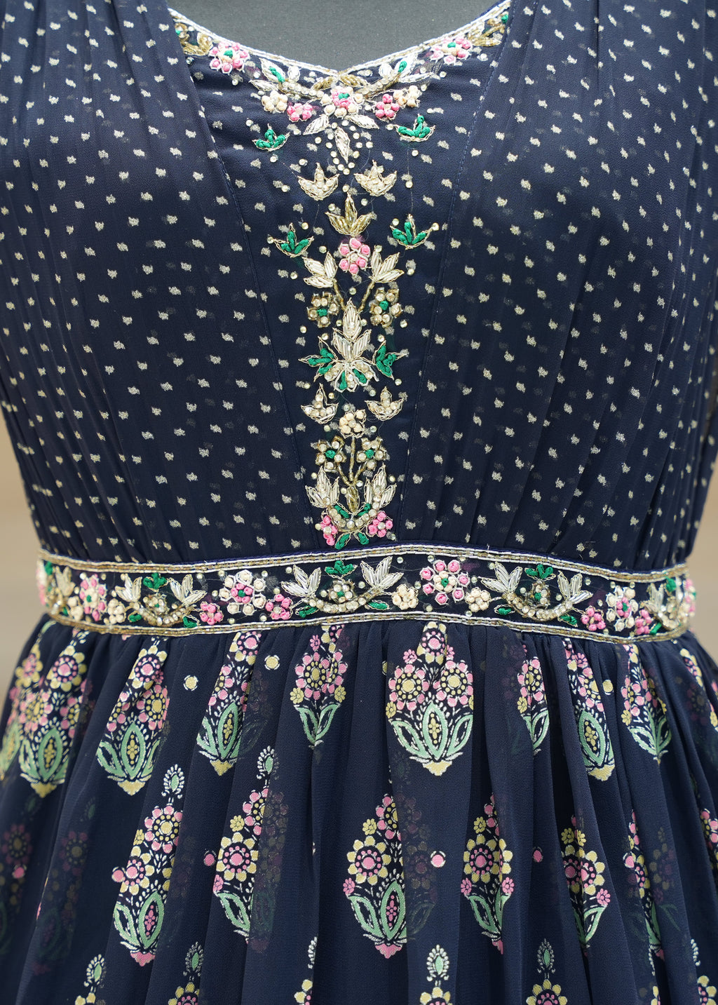 Navy blue dress with intricate white and multicolor embroidery on a neutral background