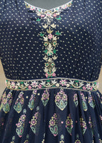 Navy blue dress with intricate white and multicolor embroidery on a neutral background