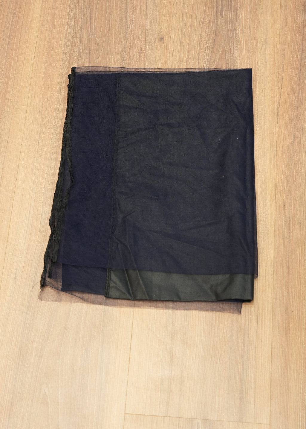 Black fabric with sheer overlay on a wooden surface