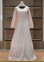 Pink evening gown on a mannequin against a wooden panel background