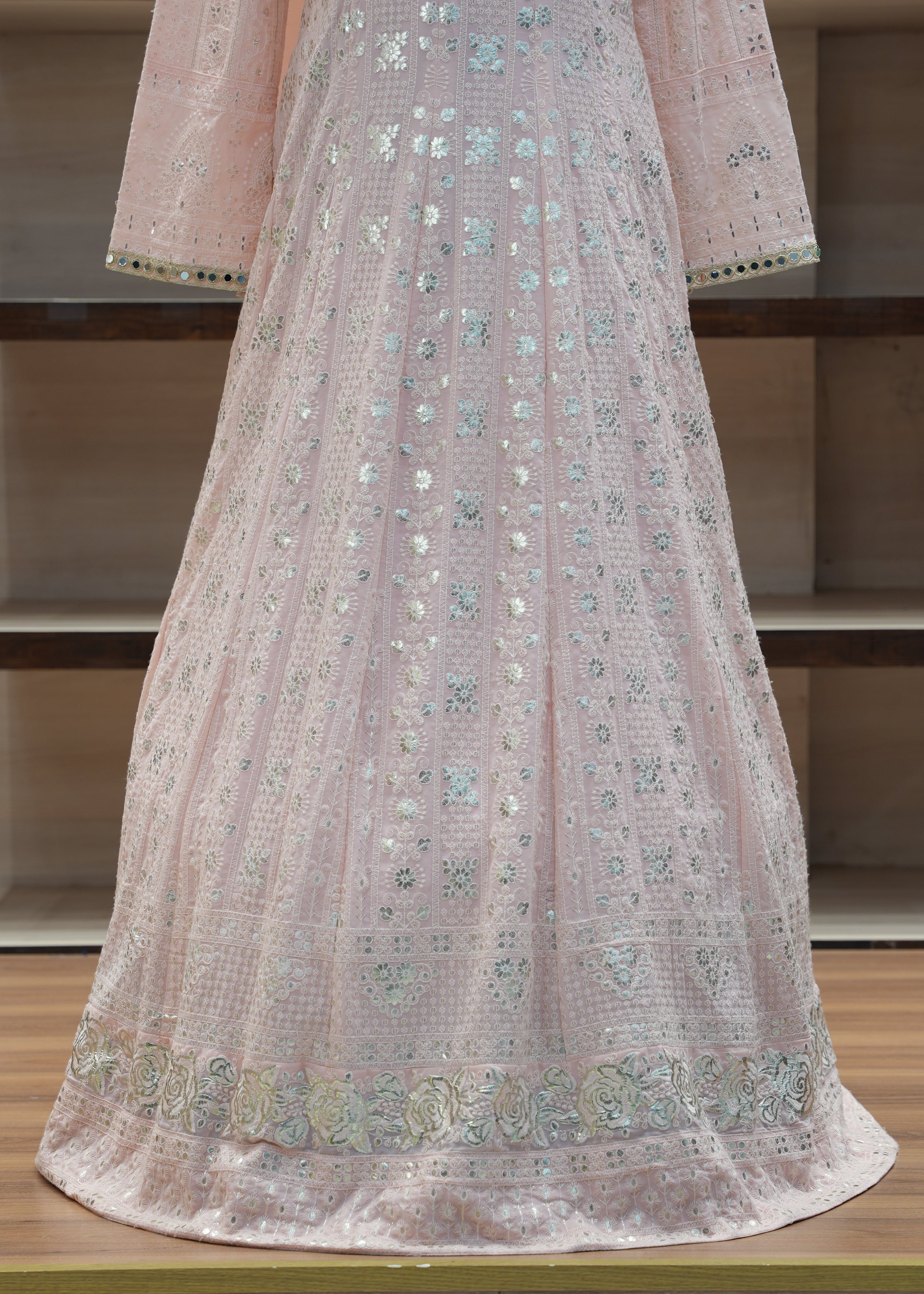 Light pink fabric with intricate patterns draped over a chair against a neutral background