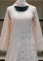 Light pink traditional outfit with floral patterns on a stand against a neutral background